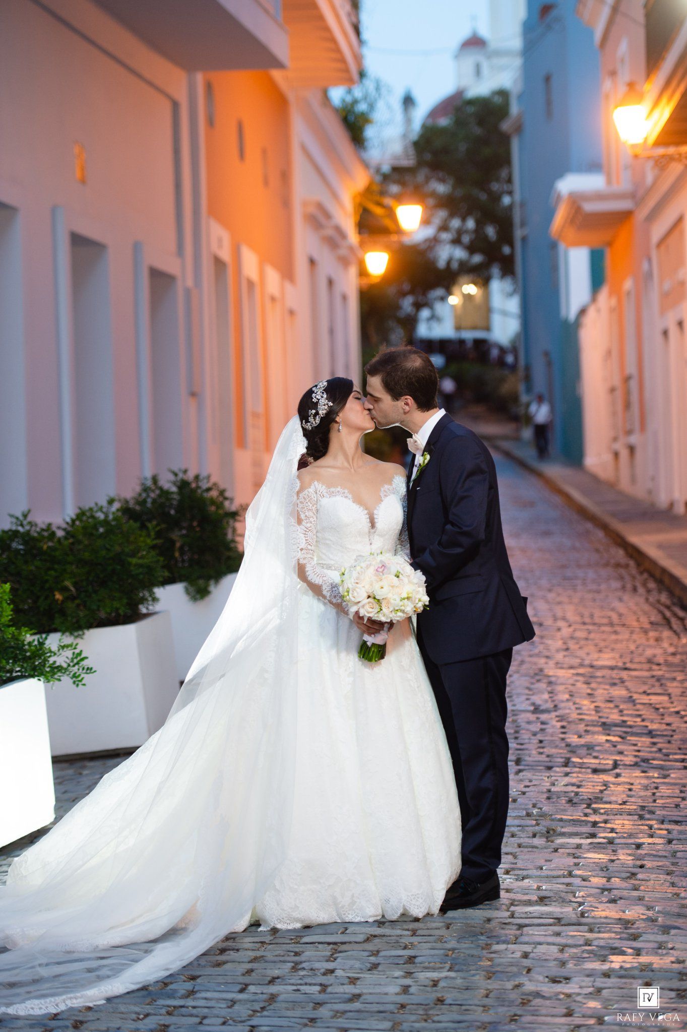 Bride and groom share a romantic kiss on a cobblestone street at dusk in Old San Juan, Puerto Rico.