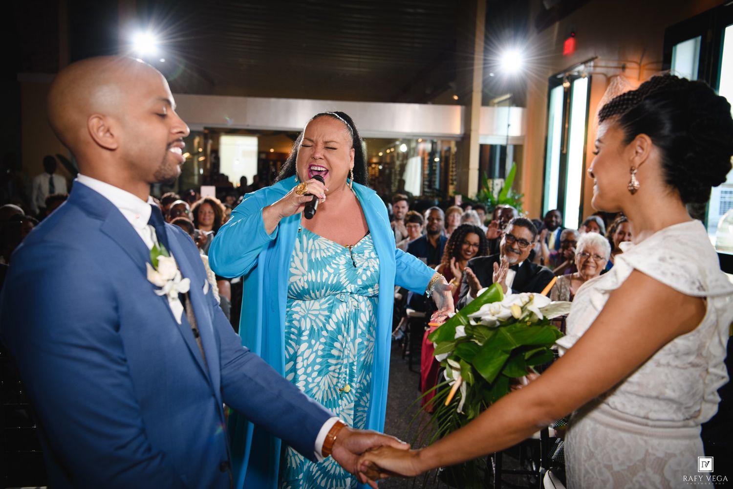 Officiant performs wedding ceremony as bride and groom hold hands at indoor venue.