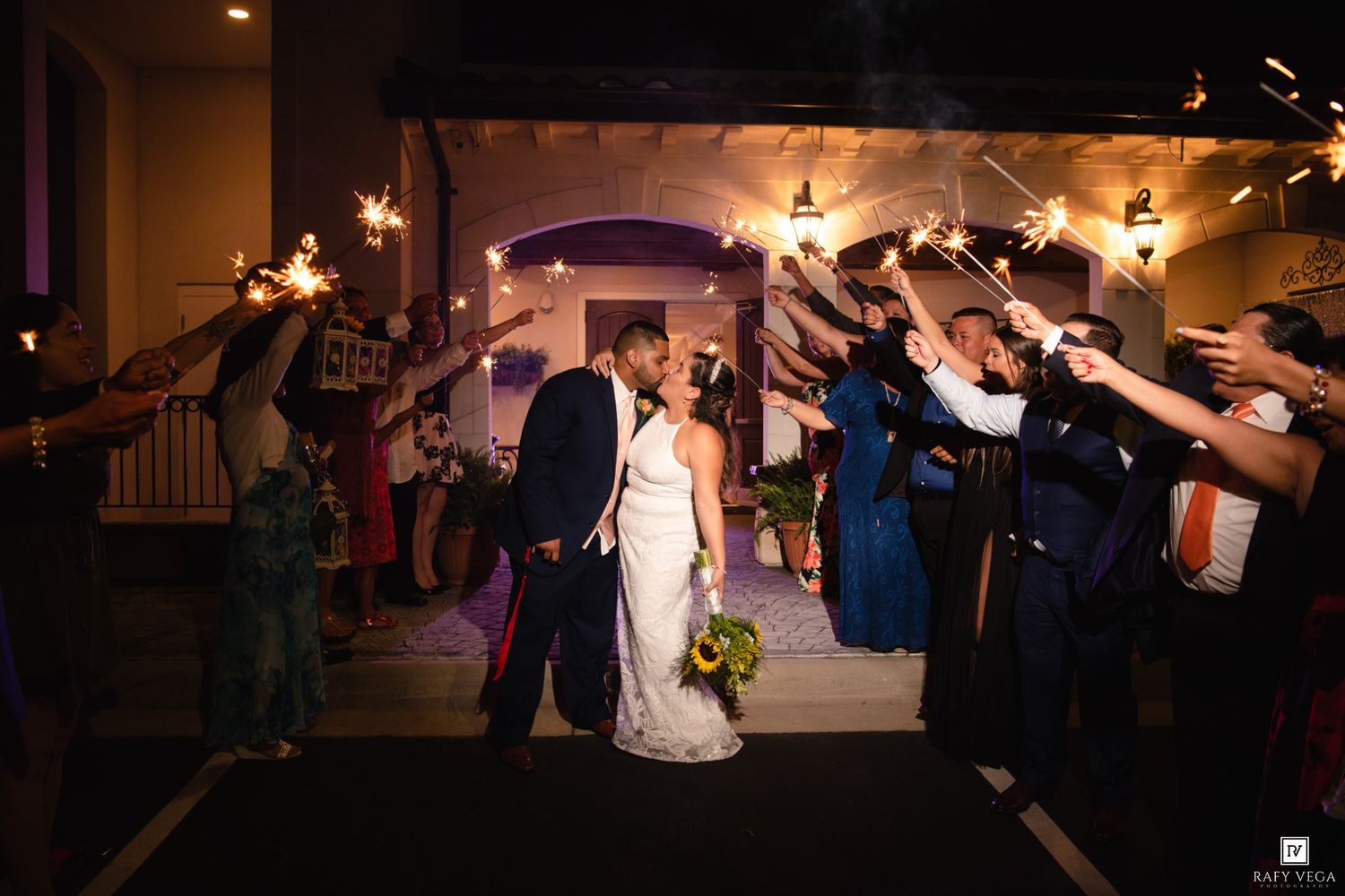 Bride and groom share a kiss during a sparkler send-off exit at their wedding celebration.