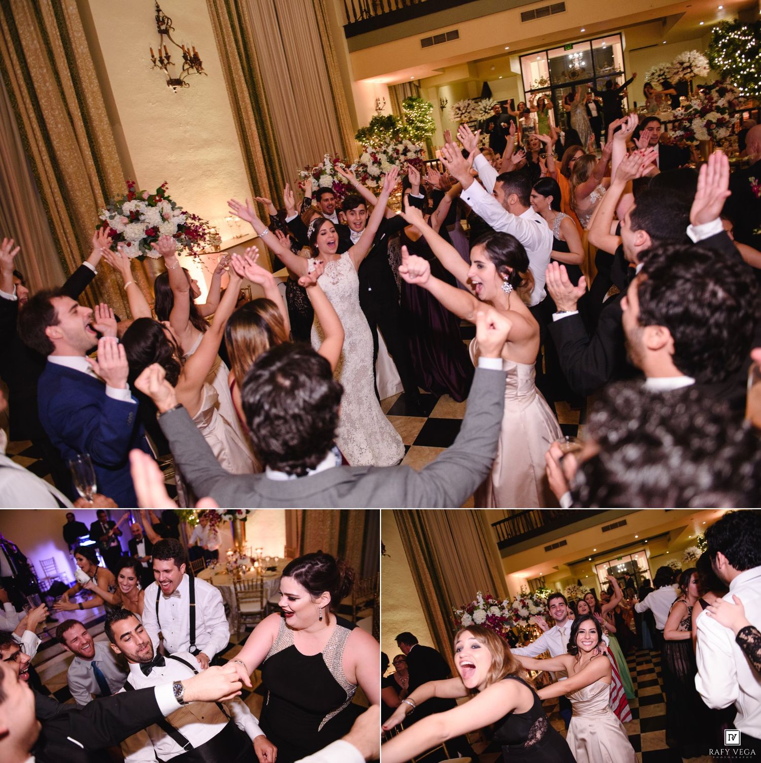 Joyful wedding reception dance floor with bride, groom, and guests celebrating with raised hands in elegant ballroom.