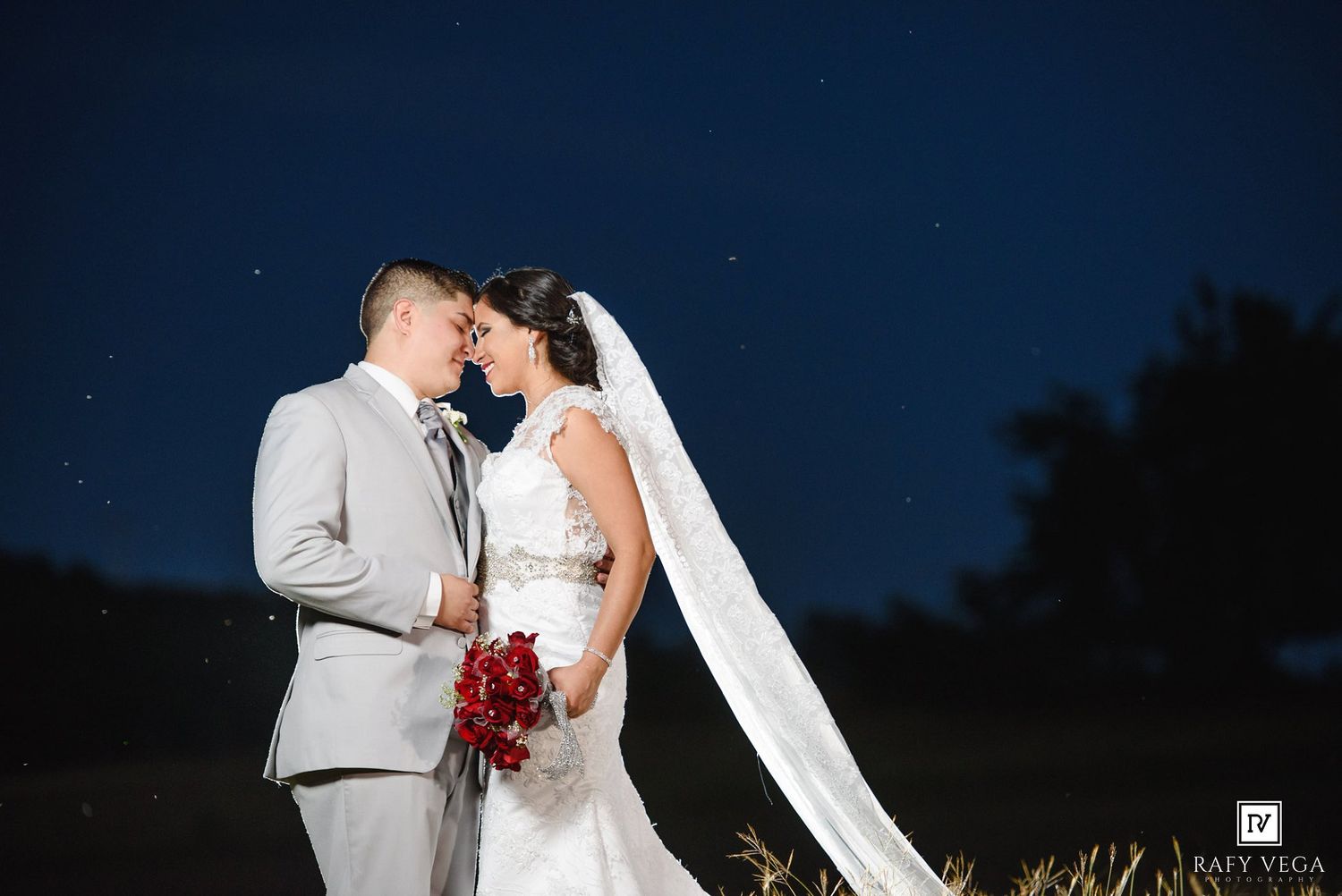 Bride and groom share romantic moment under starry night sky at outdoor wedding.