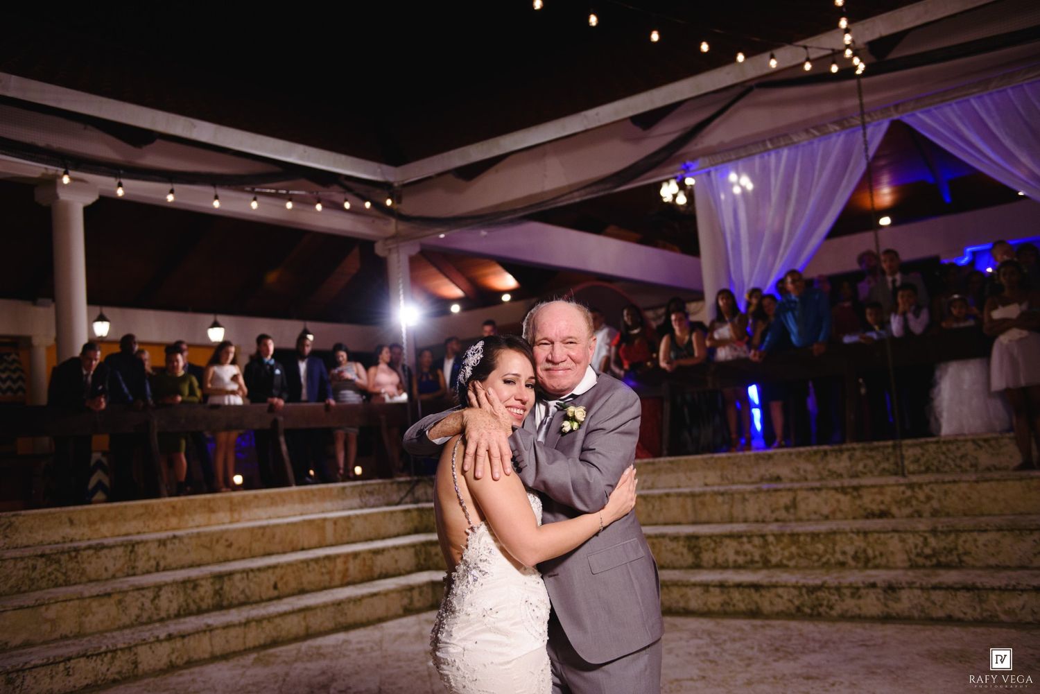 Bride shares a tender father-daughter dance on outdoor steps at evening wedding reception.