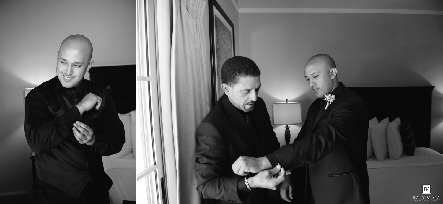 Two men in black suits preparing for a wedding, adjusting cufflinks and ties in a hotel room.