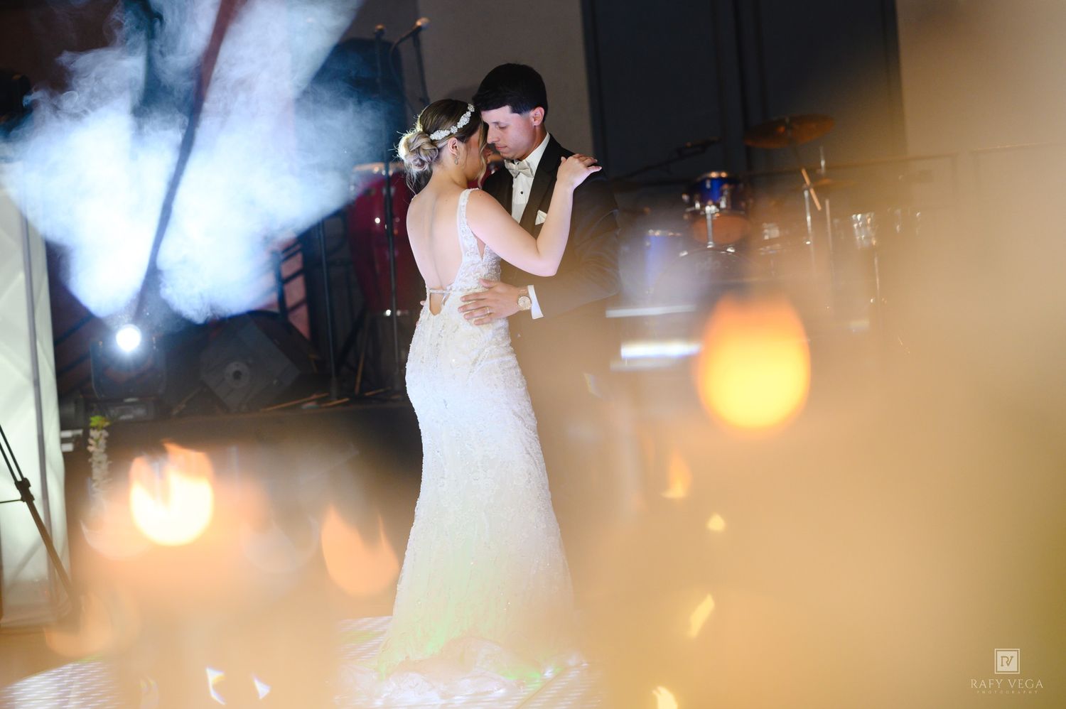 Bride and groom share their first dance surrounded by romantic golden lighting and fog at their wedding reception.