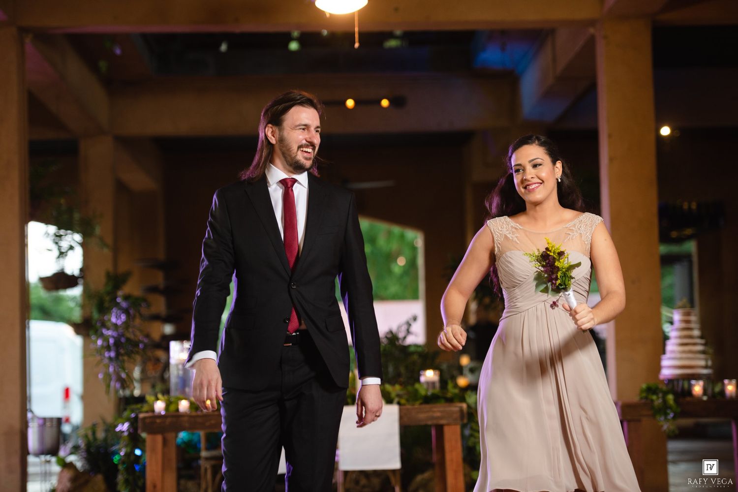 Smiling couple in formal attire walking together at a wedding reception venue.