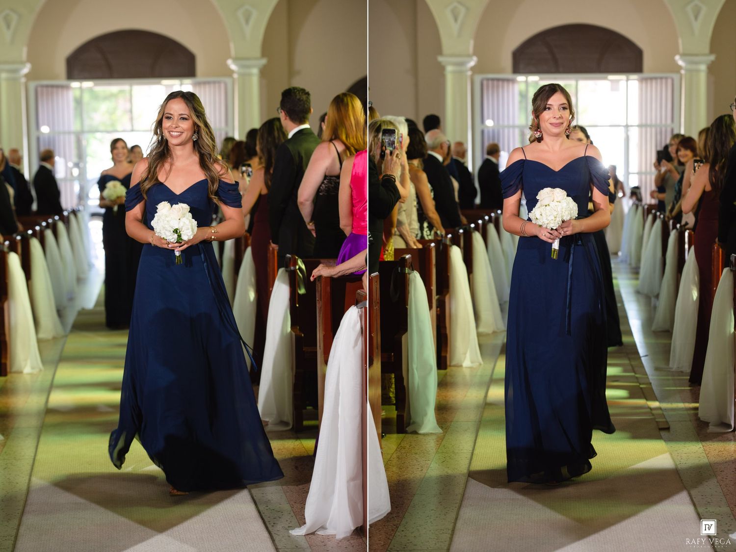 Bridesmaid in navy blue off-shoulder gown walks down wedding aisle holding white bouquet in elegant venue.