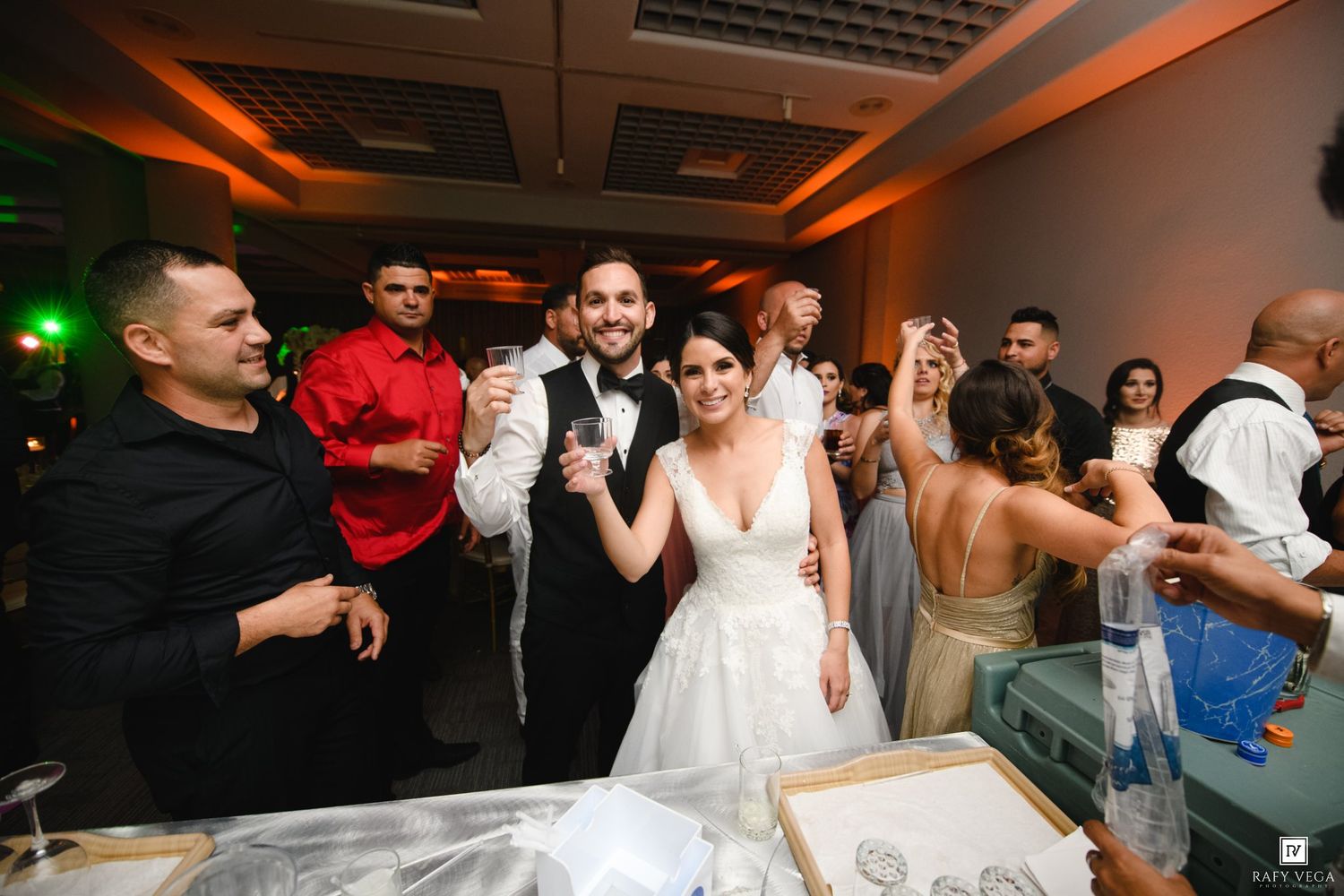 Bride and groom share a joyful moment on the dance floor surrounded by guests at their wedding reception.