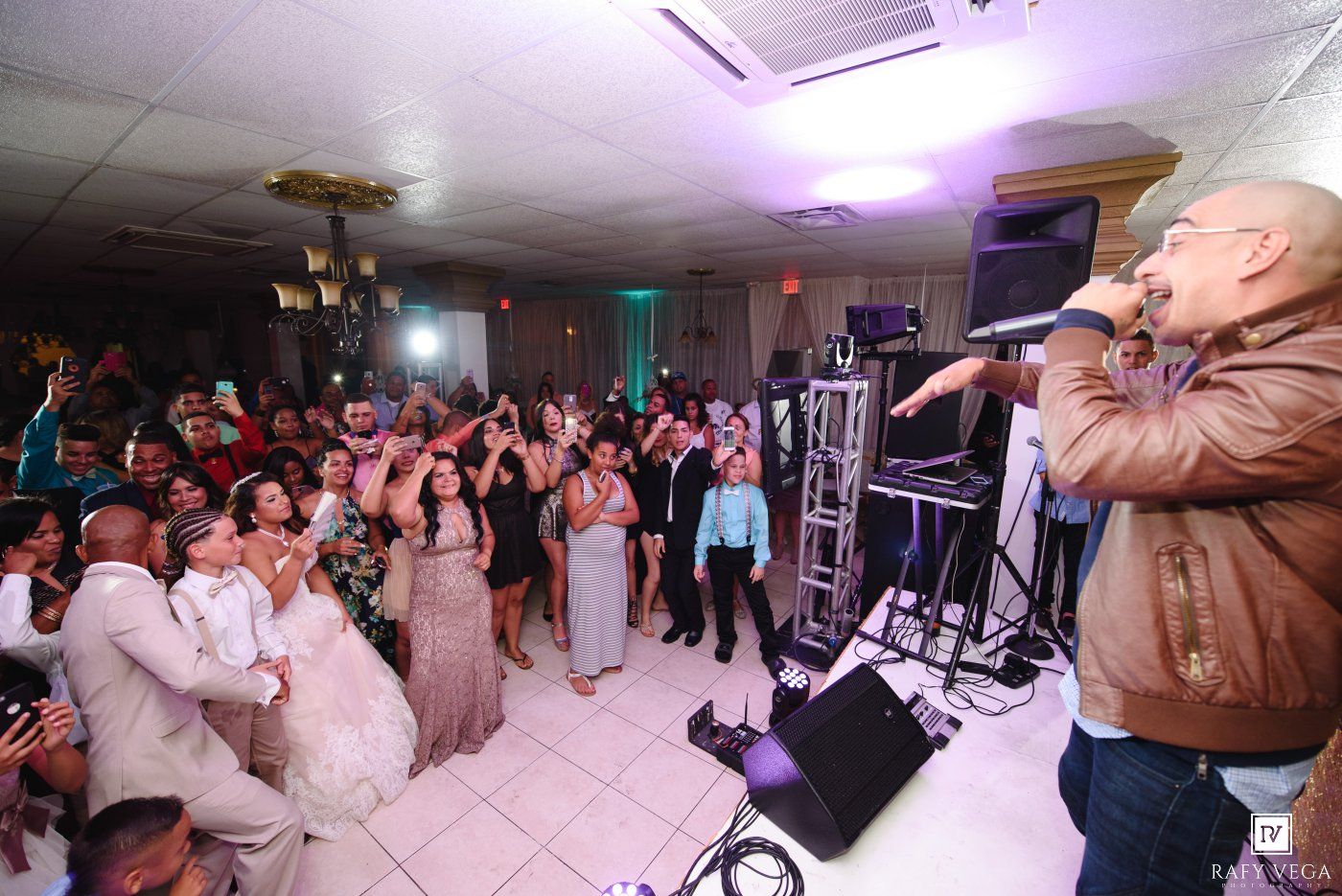 Live performer singing on stage at a lively wedding reception with guests celebrating on the dance floor.