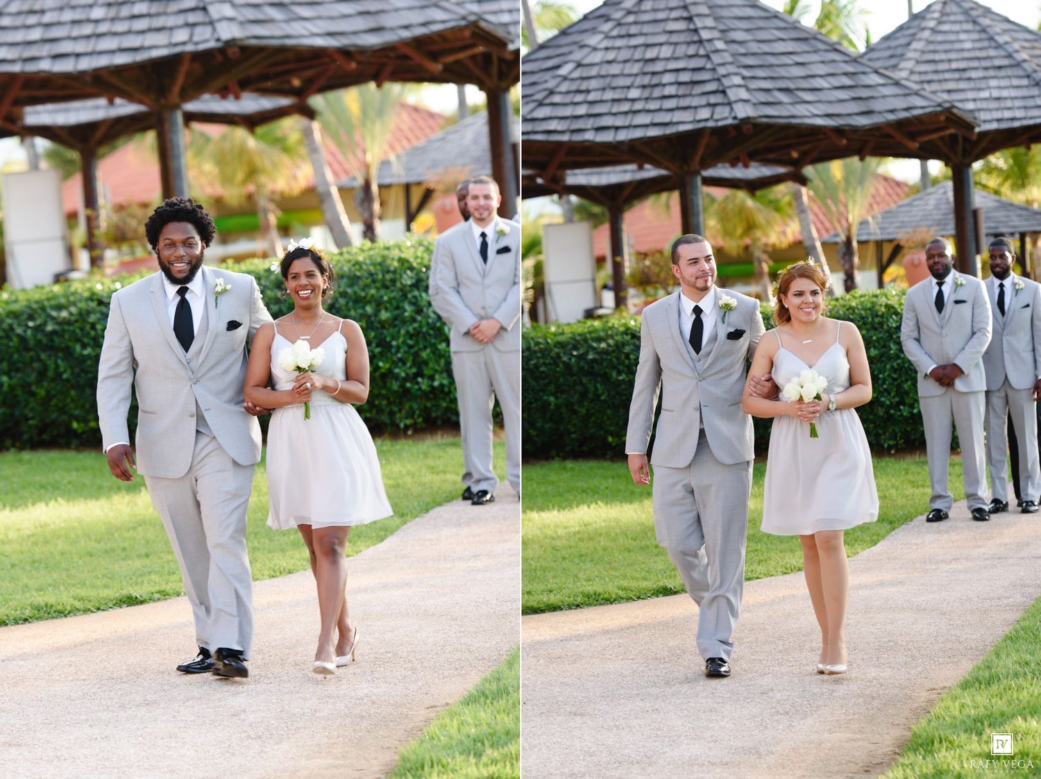Wedding couple in gray suit and white dress walking outdoors near tropical gazebo with groomsmen standing behind.
