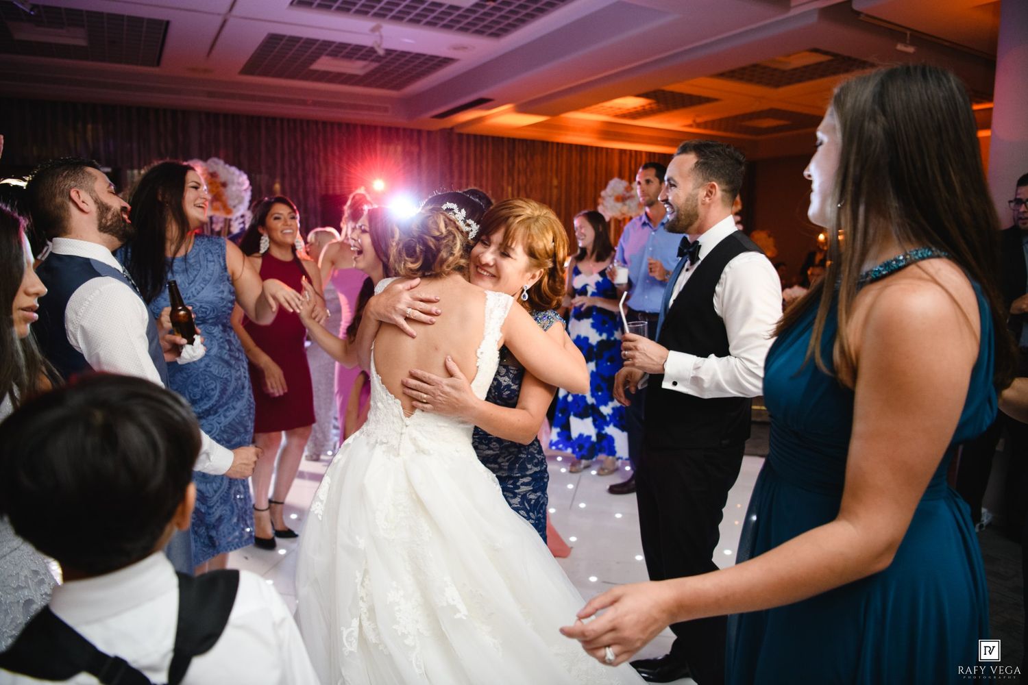 Bride and groom share a dance surrounded by guests at a lively wedding reception.