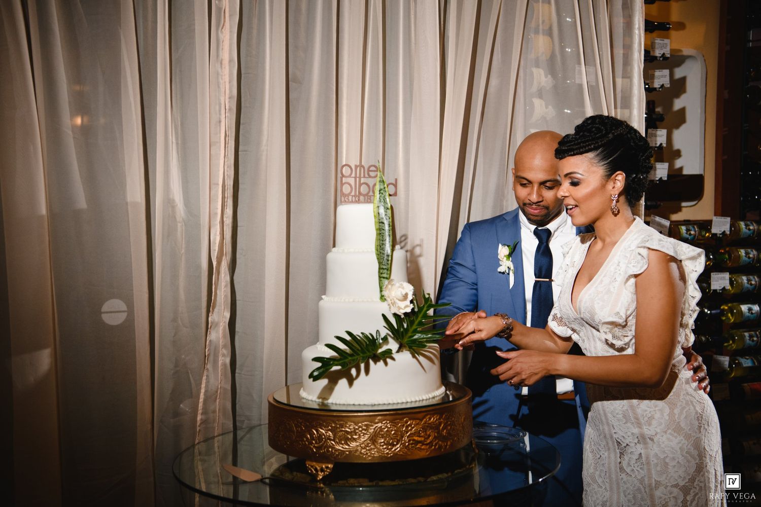 Bride and groom cutting their white wedding cake at elegant reception venue.