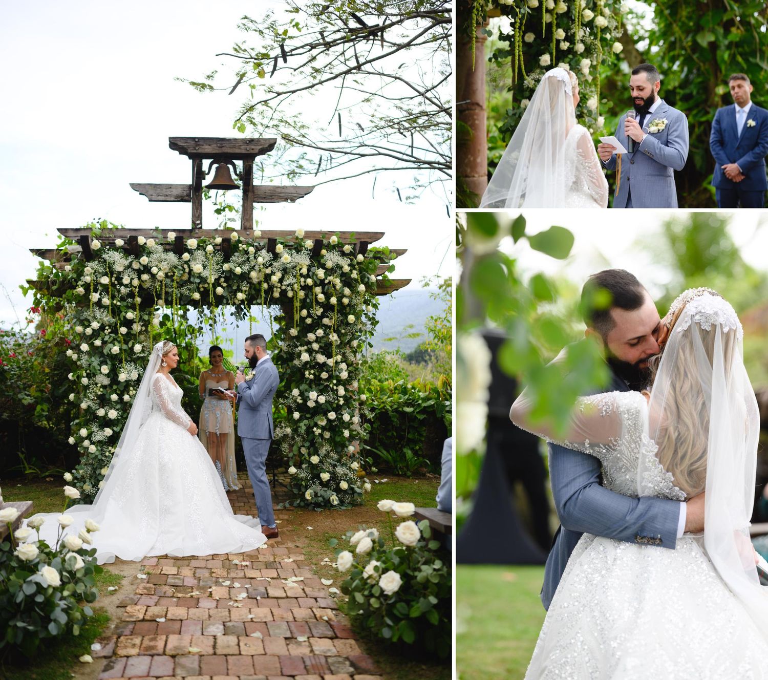 Couple embraces at elegant outdoor wedding ceremony beneath a floral arch with white roses and greenery.