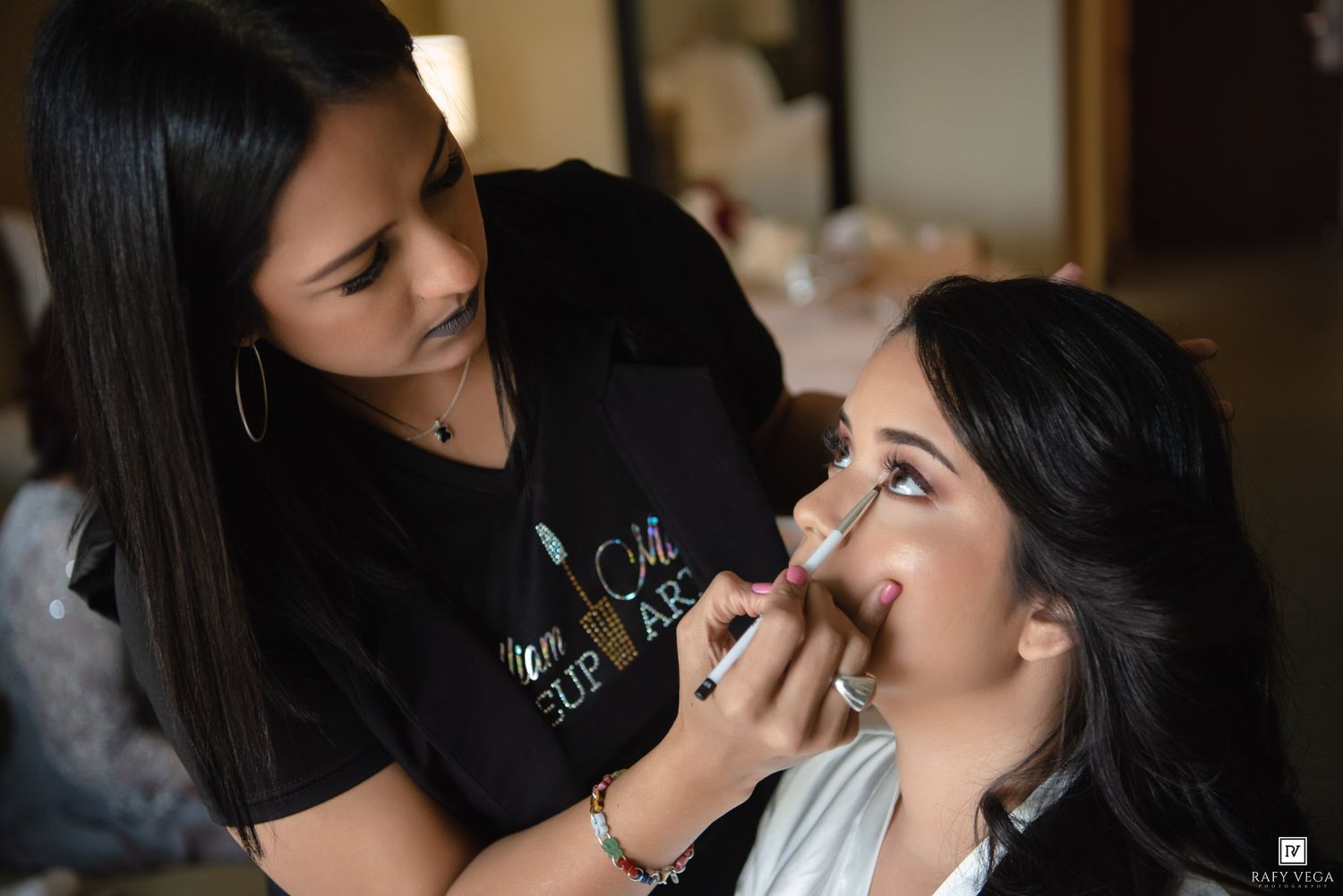 Professional makeup artist applying makeup to a bride-to-be during bridal preparation session.