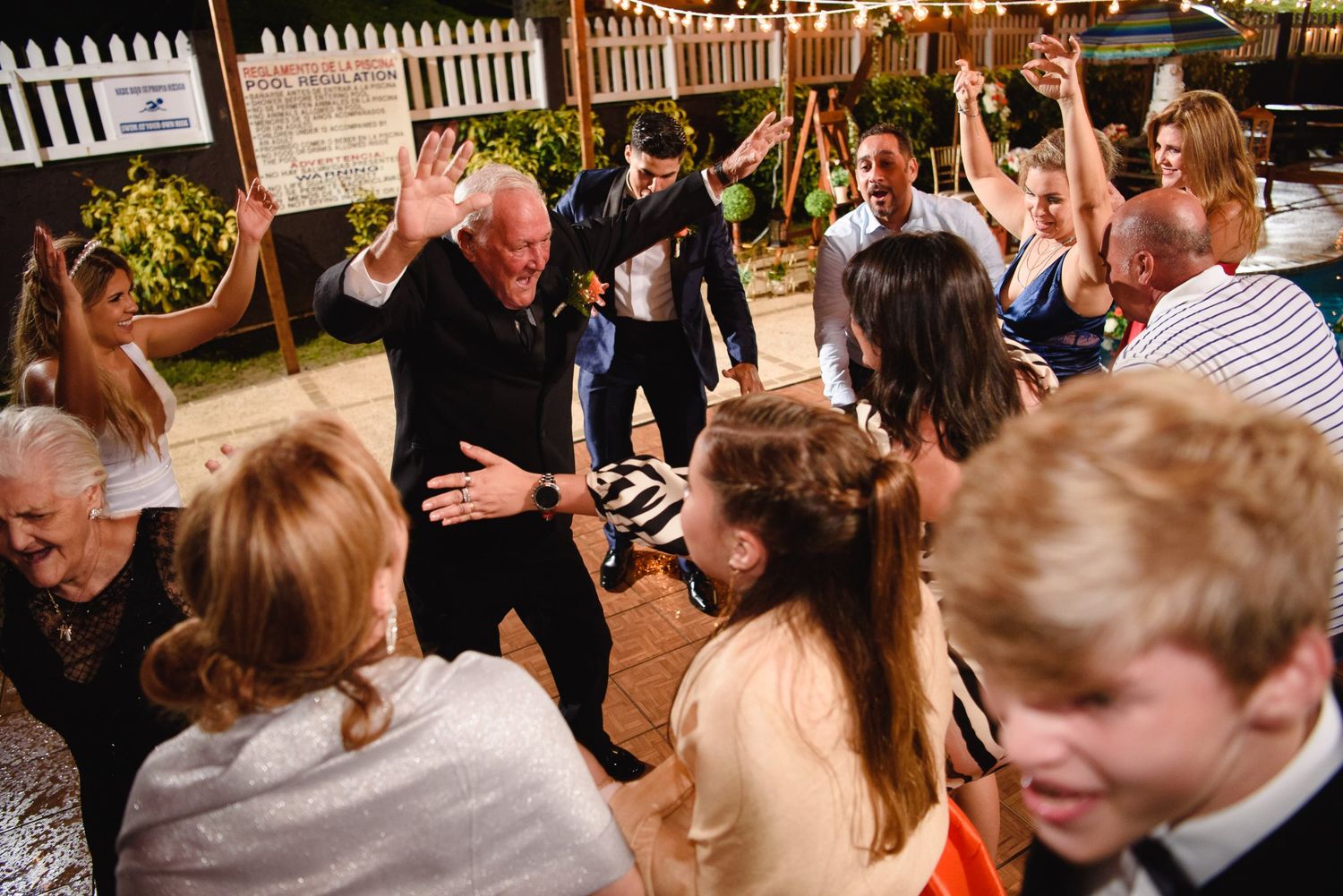 Guests dancing and celebrating at an outdoor wedding reception party at night.