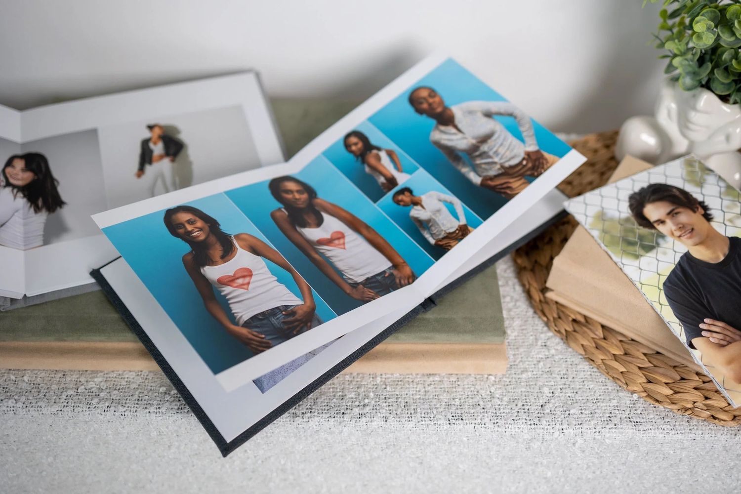 Open photo album displaying portrait photos of a woman in a white tank top on a blue background, placed on a table.