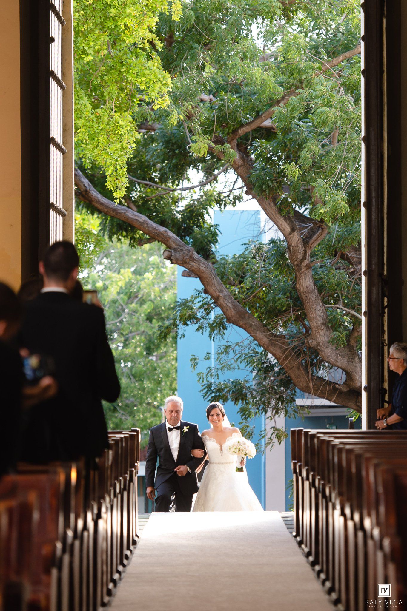 Bride walks down aisle escorted by father in elegant church wedding ceremony.