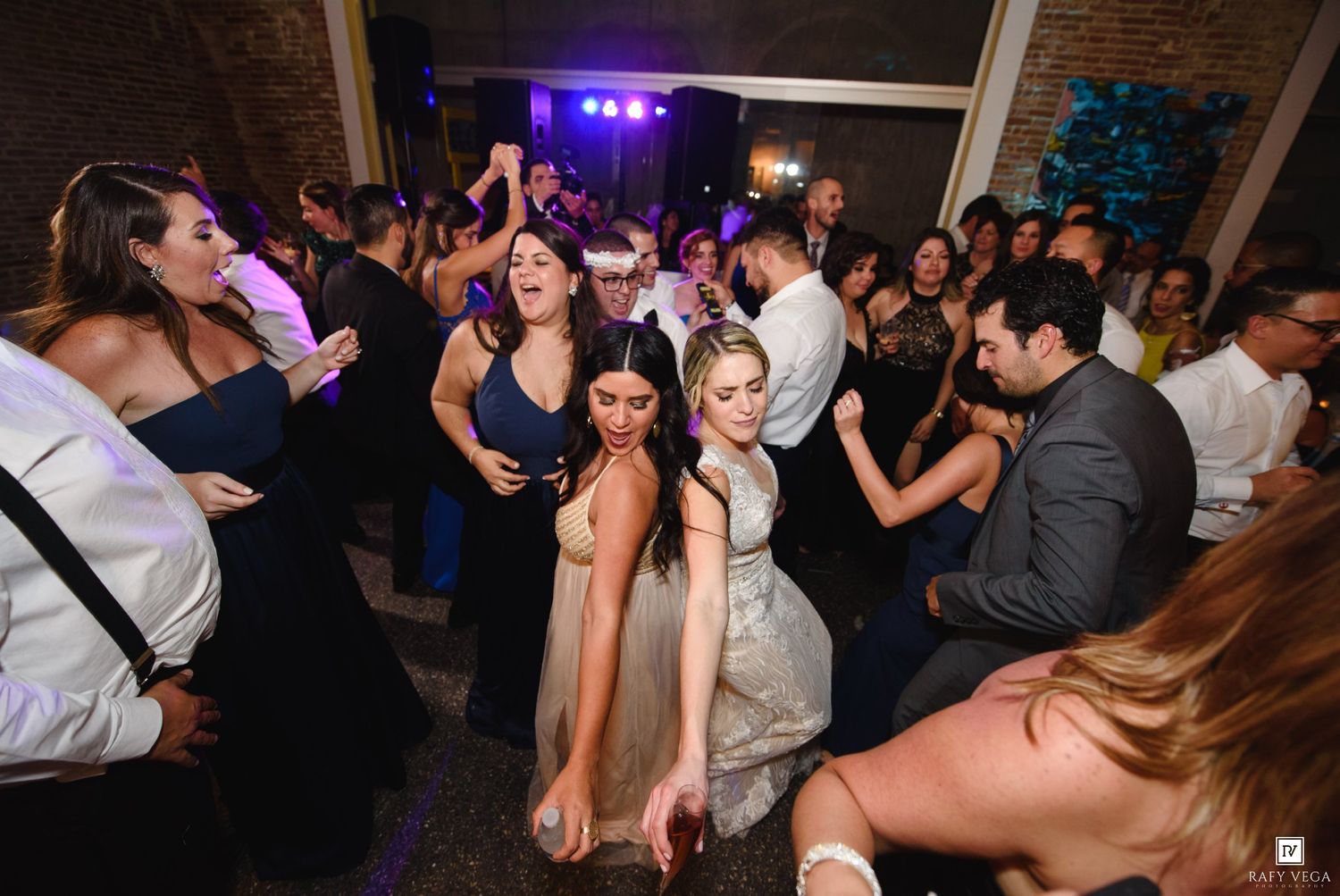 Guests dancing and celebrating at a lively wedding reception party in an elegant venue.