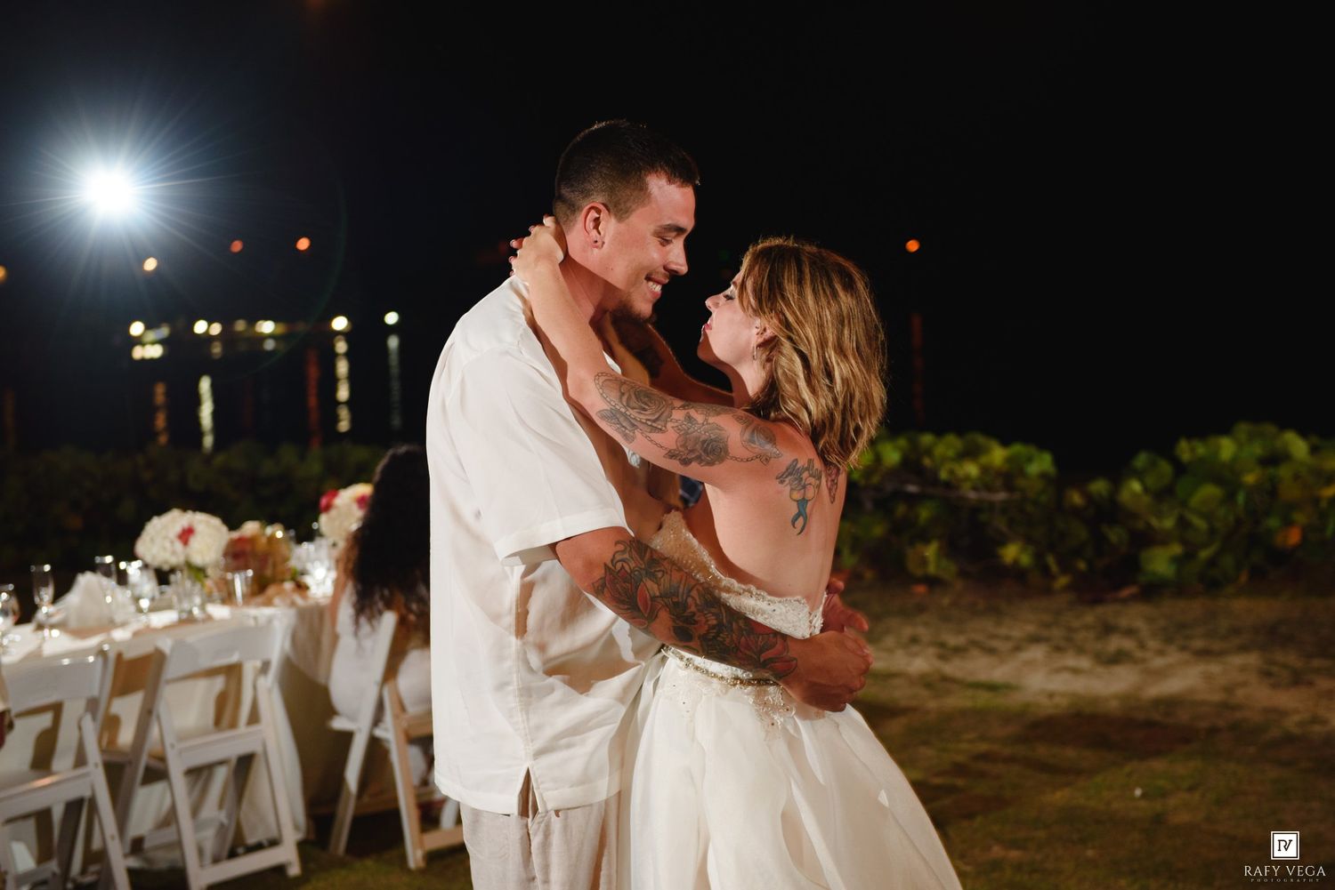 Bride and groom sharing a romantic dance outdoors at night during their beach wedding reception.