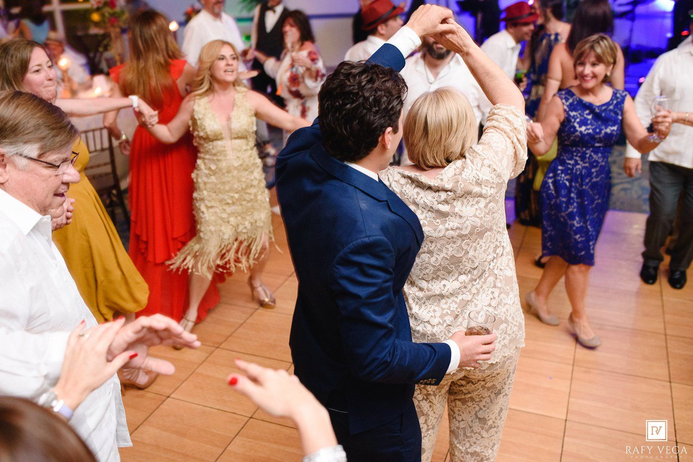 Guests dancing energetically at a lively wedding reception celebration.