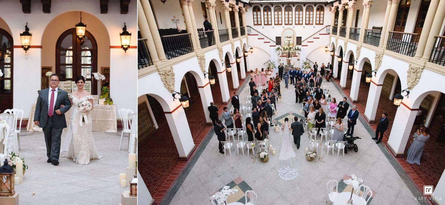 Elegant wedding ceremony in a grand arched venue with guests gathered, featuring white floral decor and a stunning indoor courtyard.