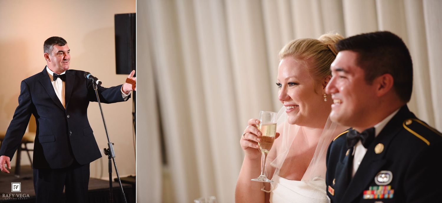 Military groom and bride smiling during wedding reception toast while man in tuxedo gives speech at microphone.