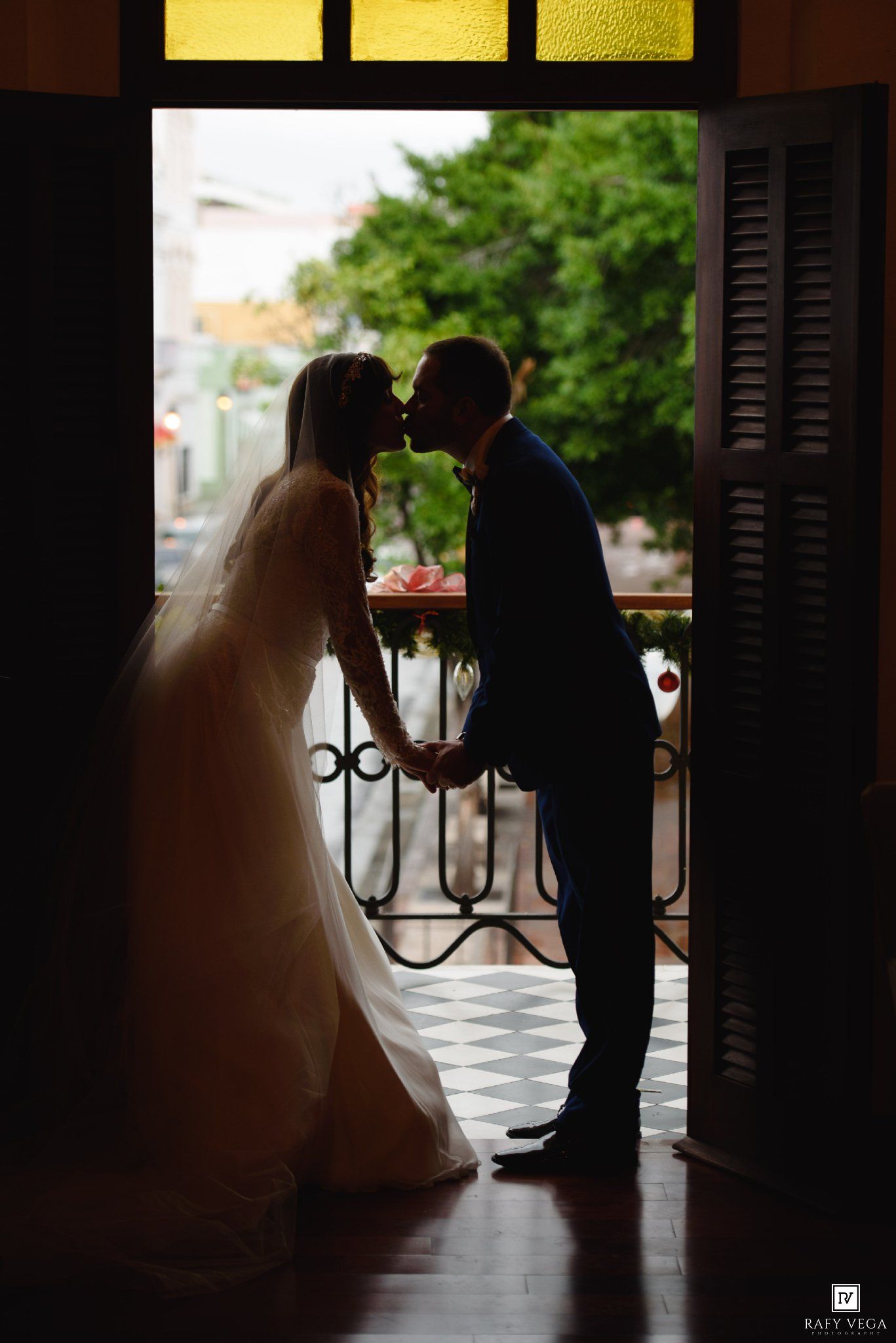 Silhouette of a bride and groom sharing a romantic kiss in a doorway on their wedding day.