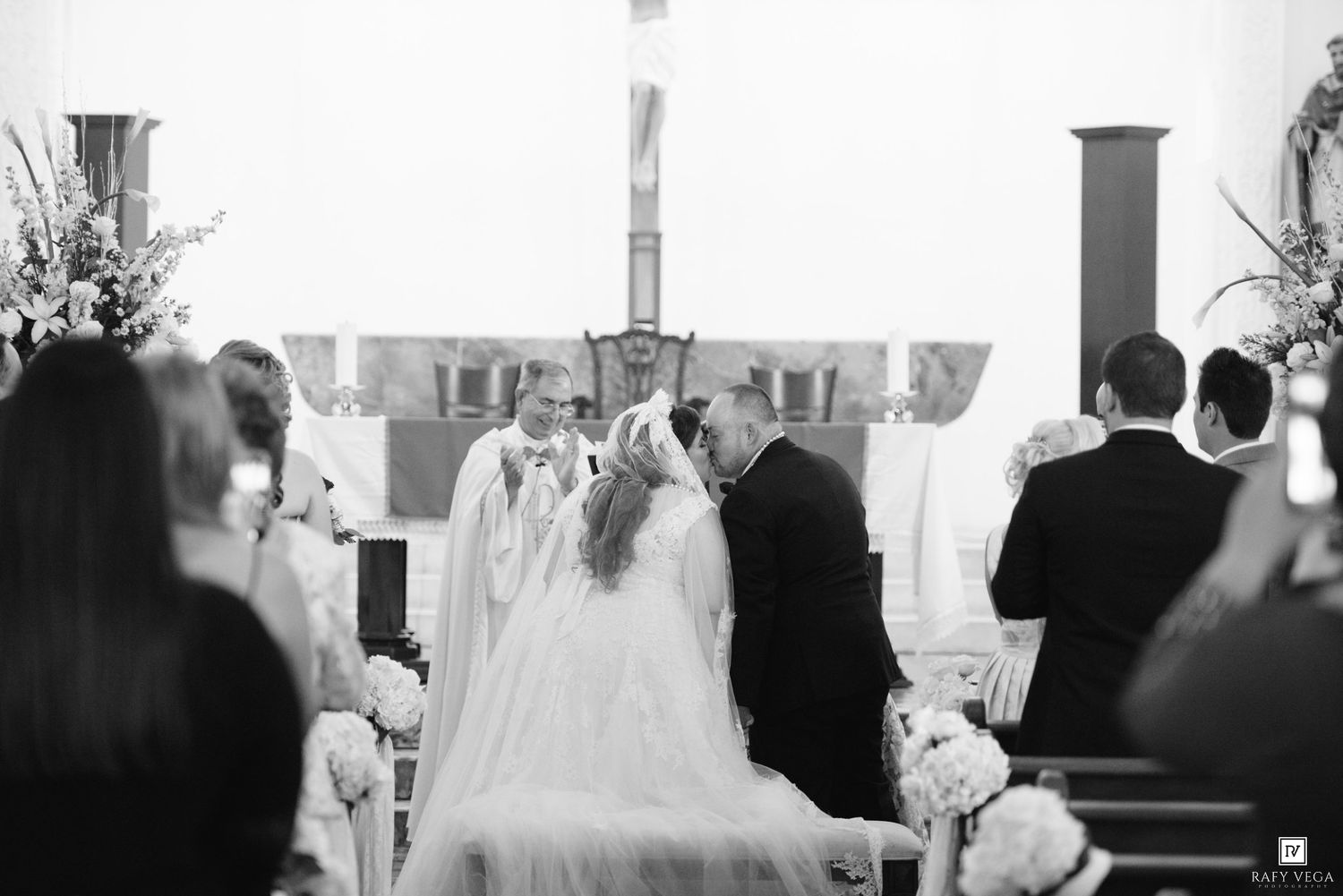 Black and white photo of a bride and groom at the altar during a church wedding ceremony with guests seated in pews.