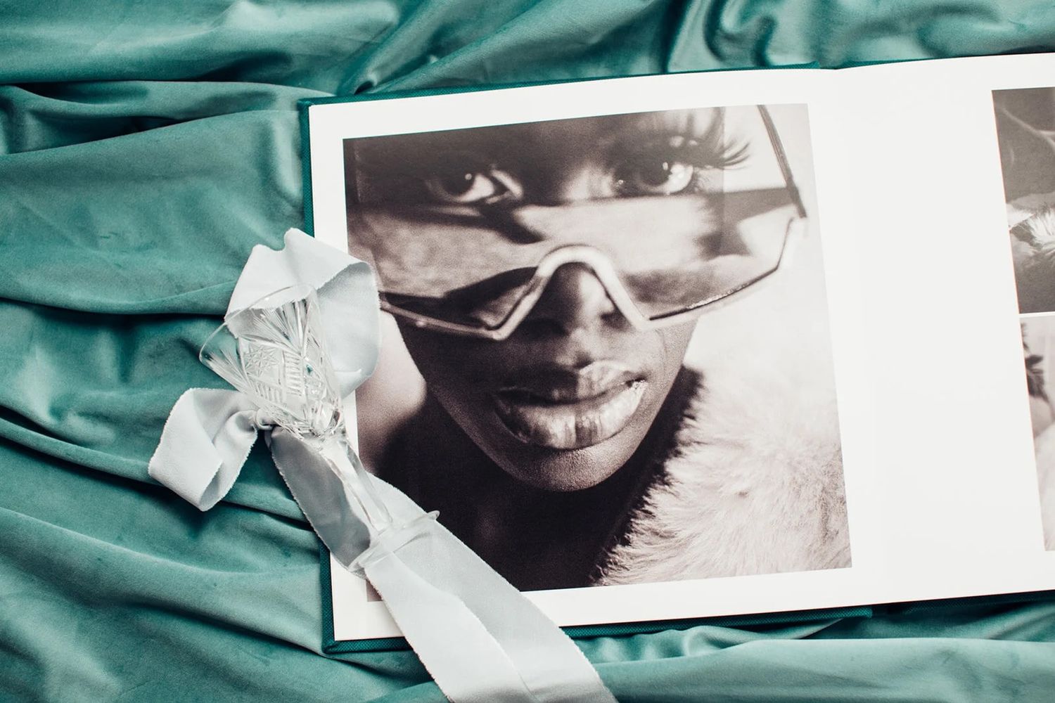 Black and white portrait photo in an open book on teal satin fabric with white ribbon bow.