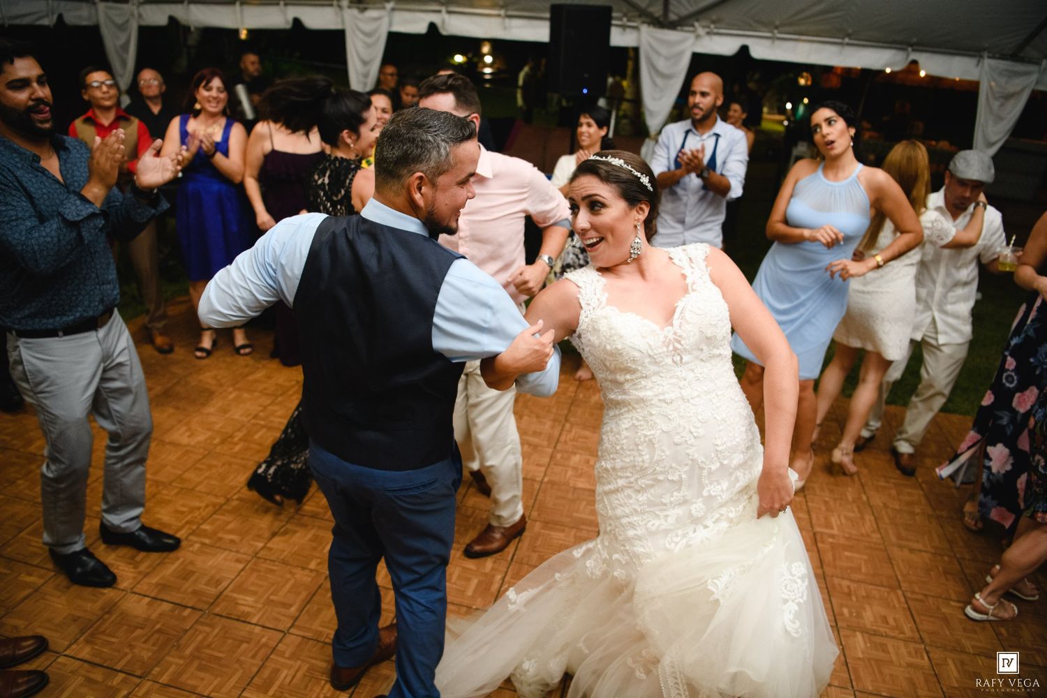 Bride and groom share a joyful dance surrounded by cheering guests at an elegant outdoor wedding reception.