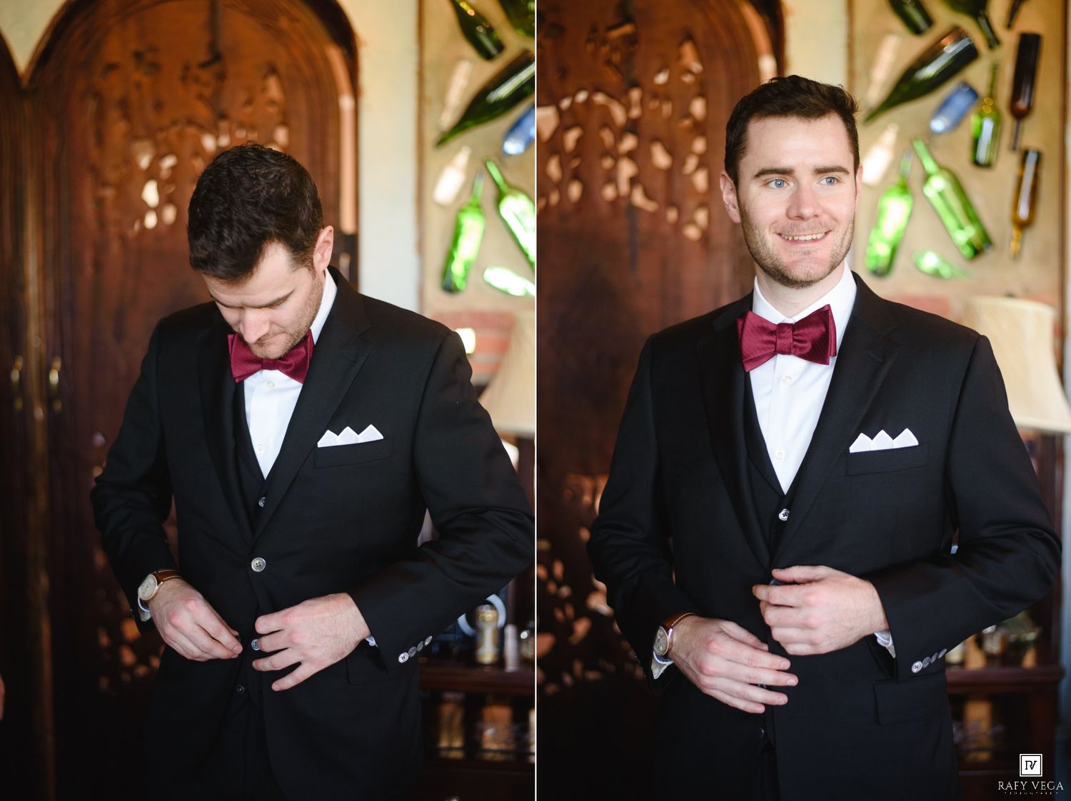 Groom in black tuxedo with burgundy bow tie and white pocket square buttoning jacket before wedding ceremony.