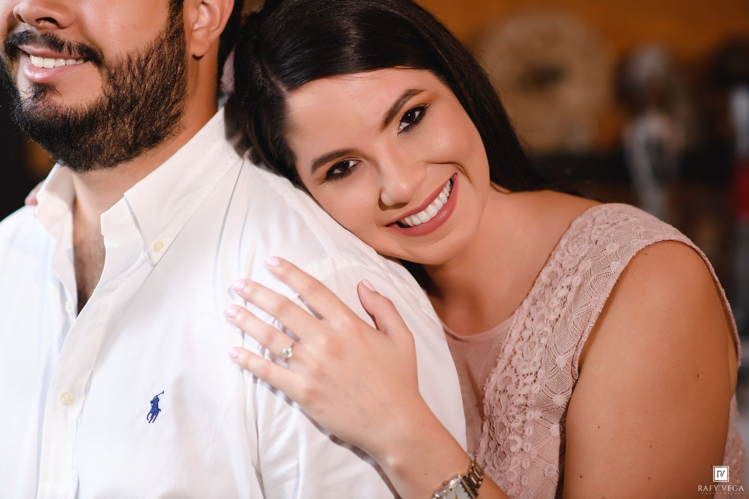 Smiling bride-to-be leans on her fiance showing off her engagement ring during a romantic couples photo session.