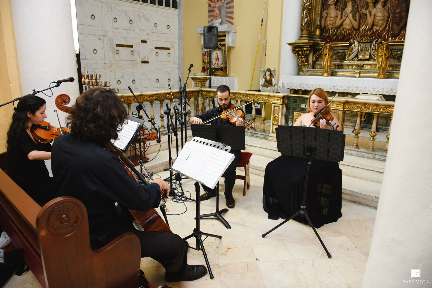 String quartet performing classical music in an ornate church with golden altar backdrop.