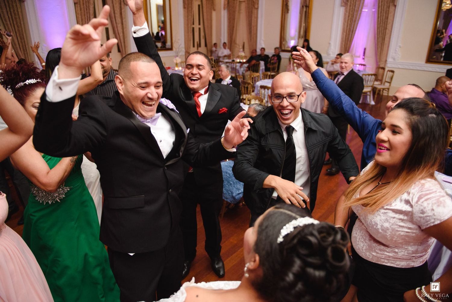 Joyful wedding guests dancing and celebrating at lively wedding reception in elegant ballroom.