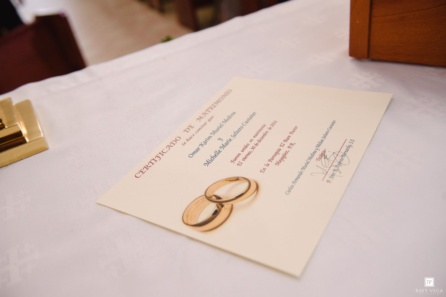 A gold wedding ring certificate displayed on a white table at a marriage ceremony.