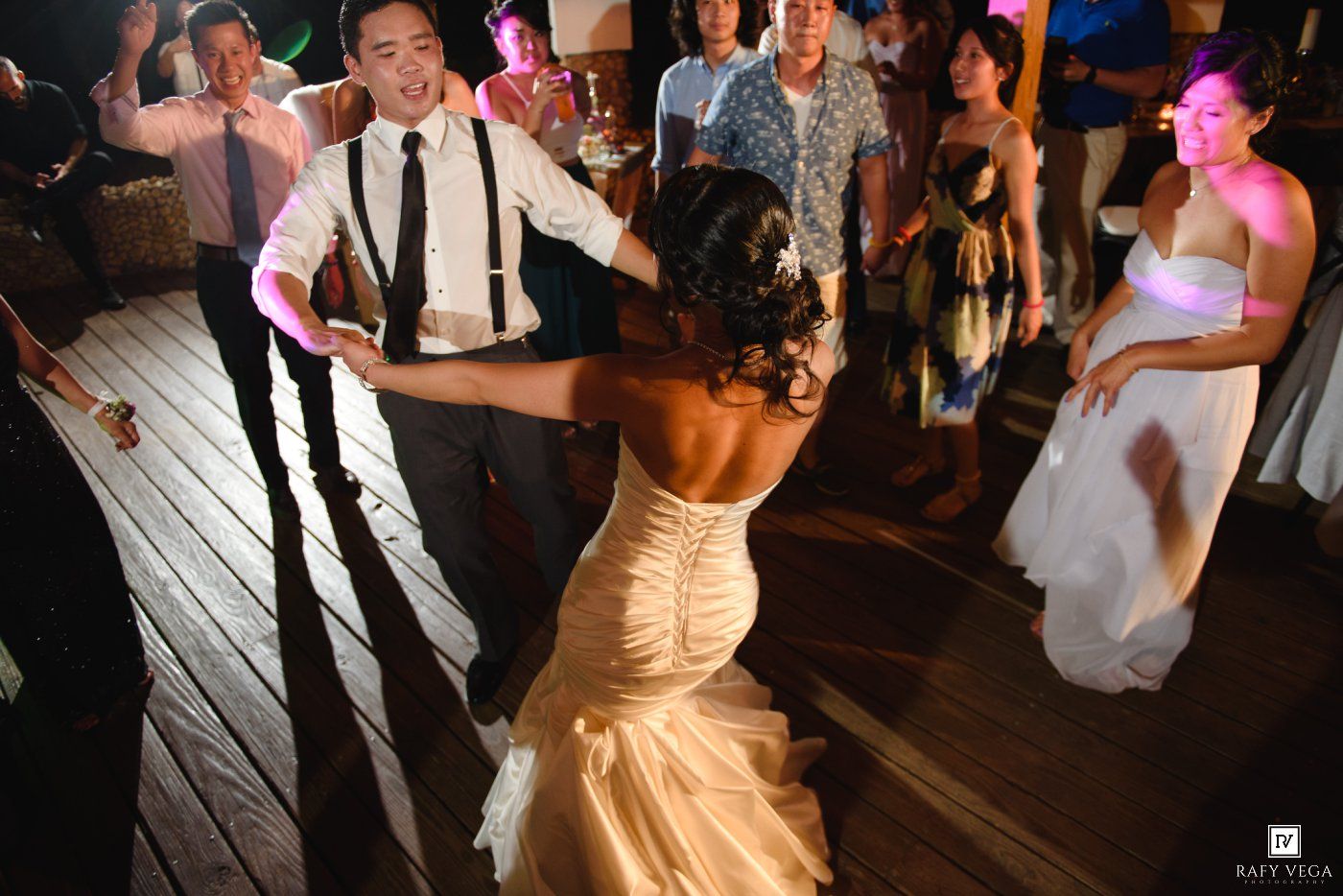 Bride and groom share energetic first dance on wooden dance floor at wedding reception.