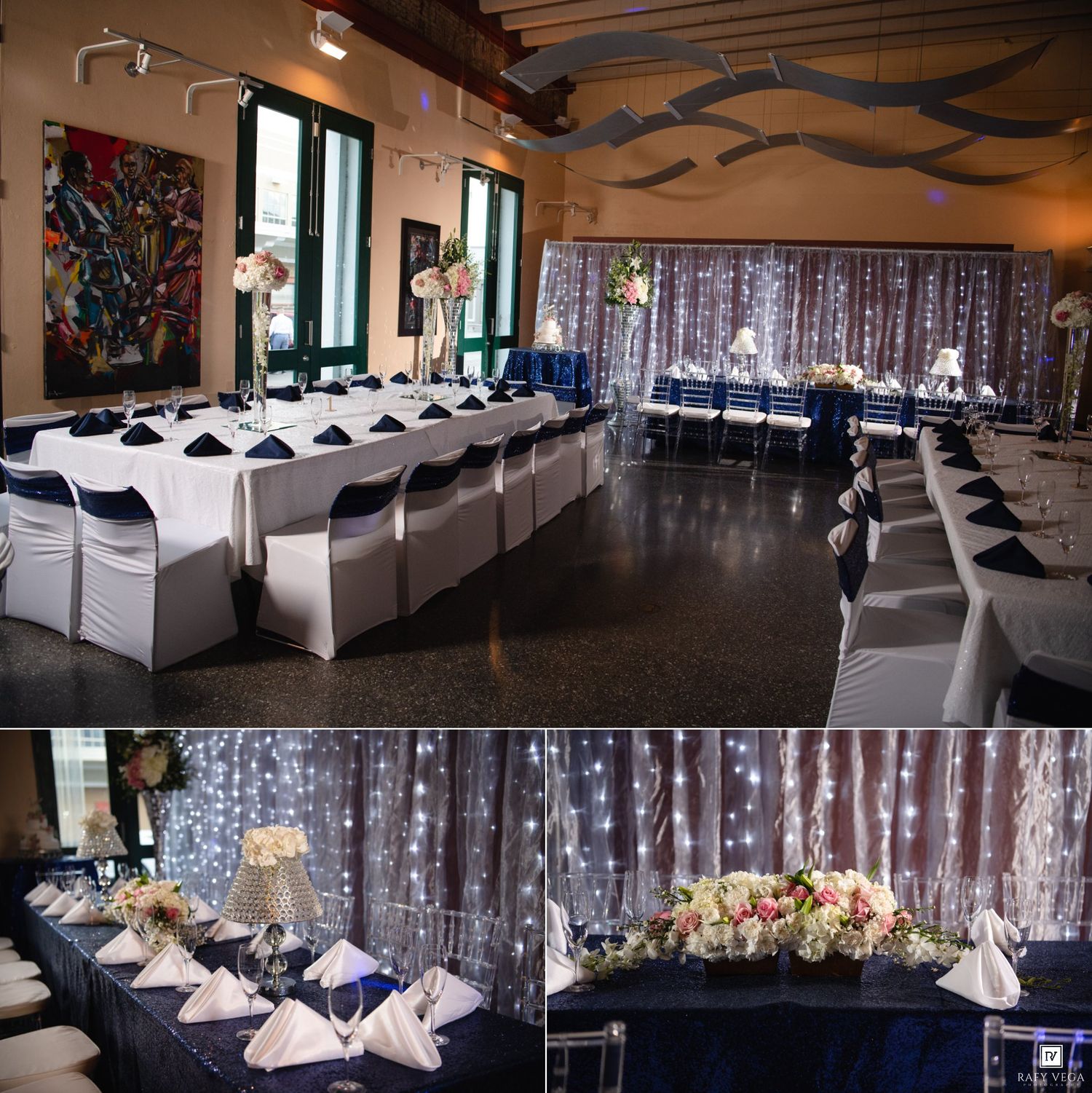 Elegant wedding reception venue with navy blue and white table settings, floral centerpieces, and twinkling fairy light backdrop.