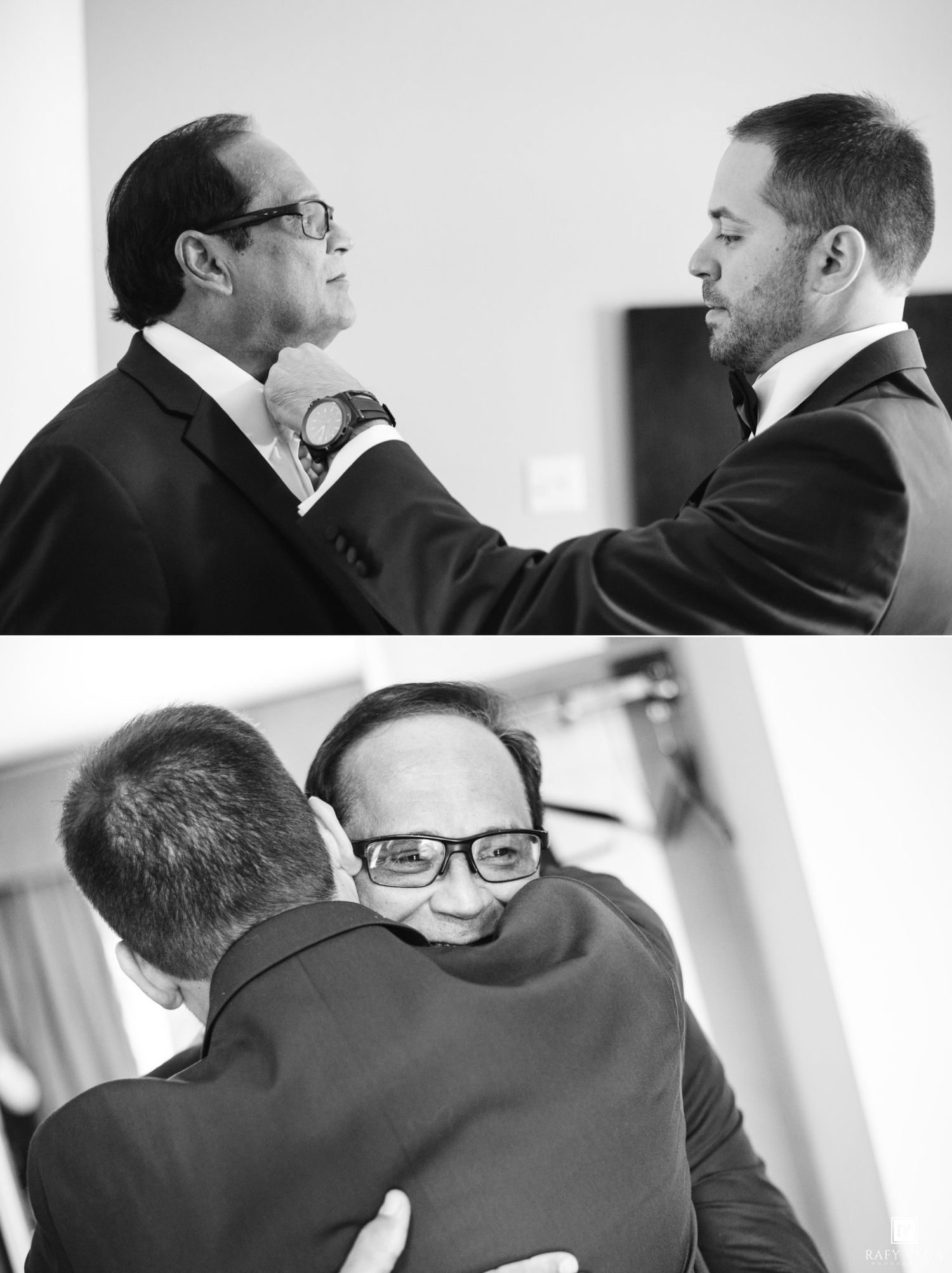 Two men in suits share a heartfelt hug and tie adjustment moment in black and white wedding photography.