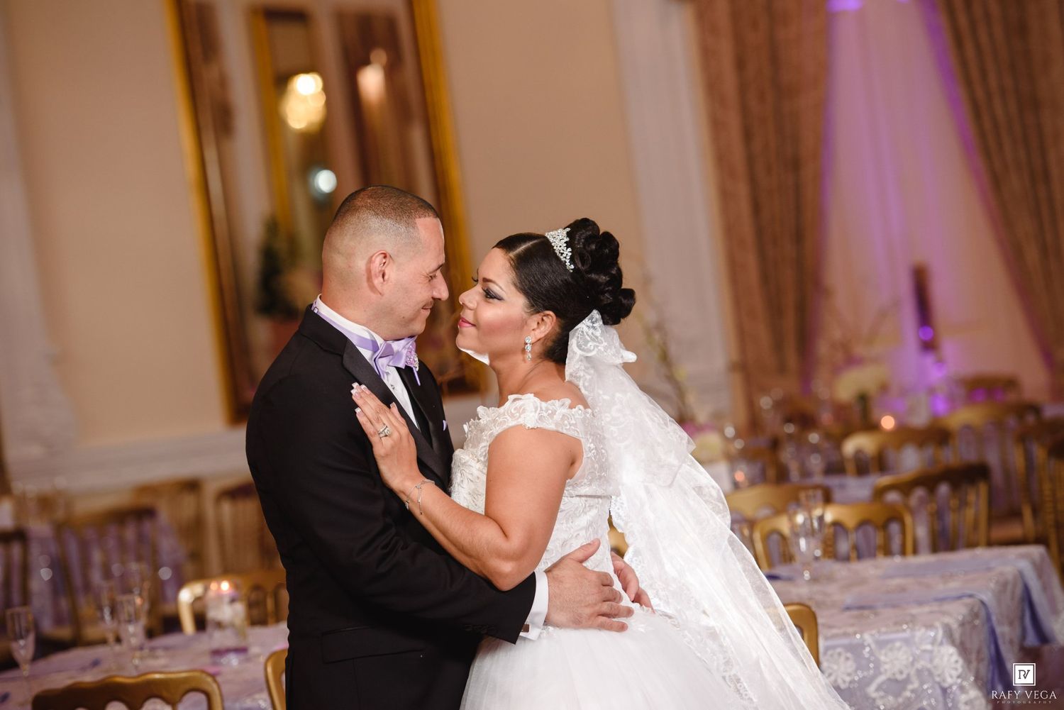 Bride and groom share a romantic moment during their elegant wedding reception in a grand ballroom.