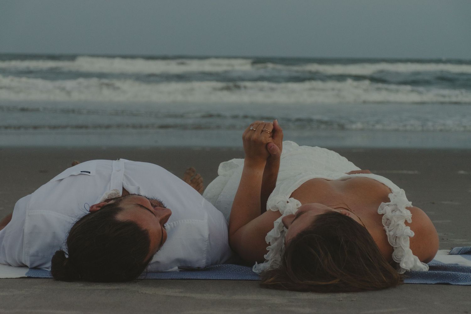 Wide shot of couple lying on beach relaxed candid moment by ocean
