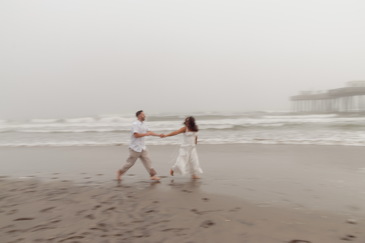Couple running along shoreline playful moment South Jersey beach session