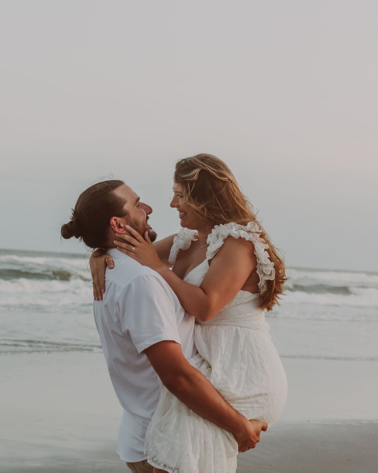 Couple embracing on beach during romantic engagement session South Jersey