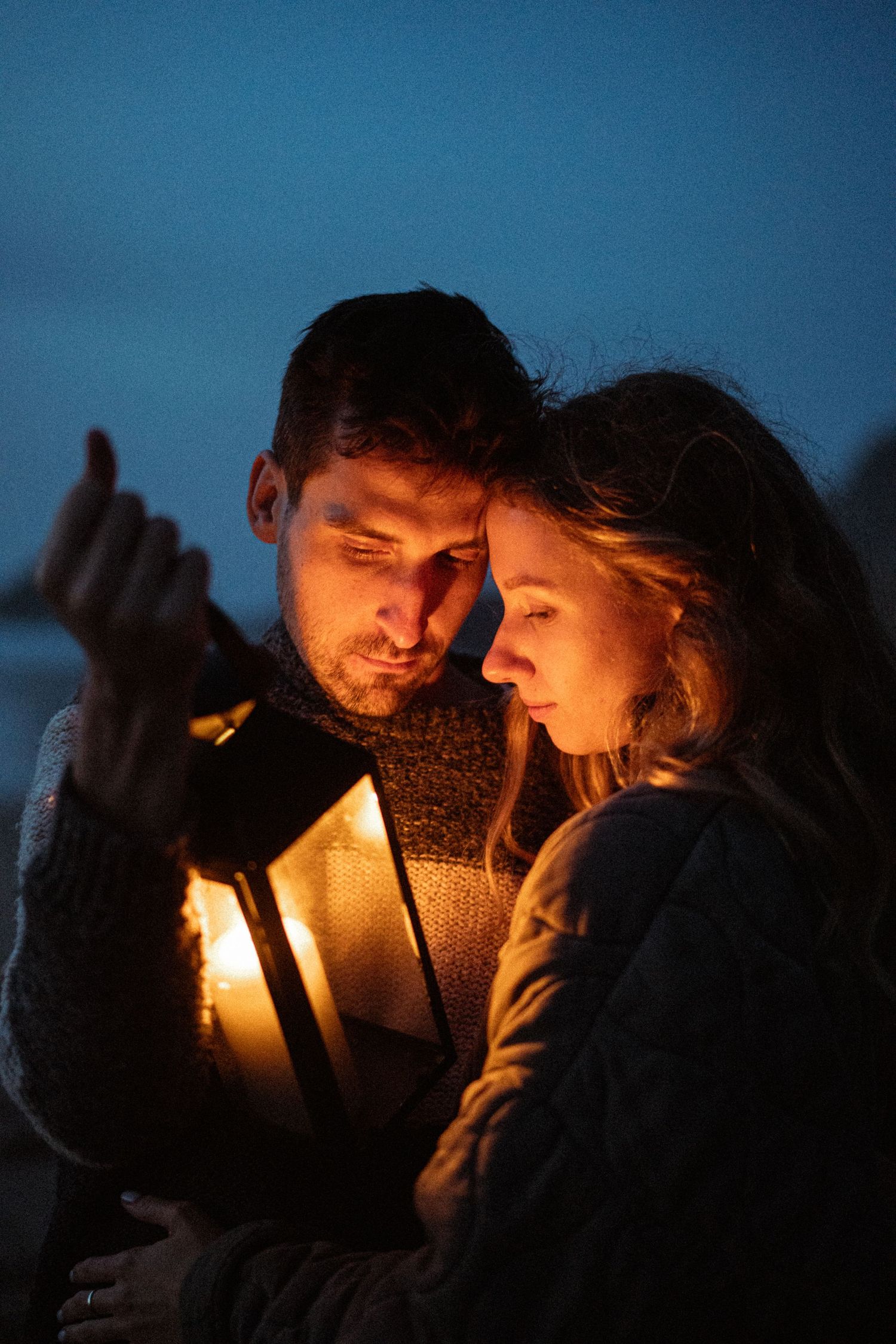 A couple sharing a tender moment by candlelight on the beach at dusk, couples photography Portugal