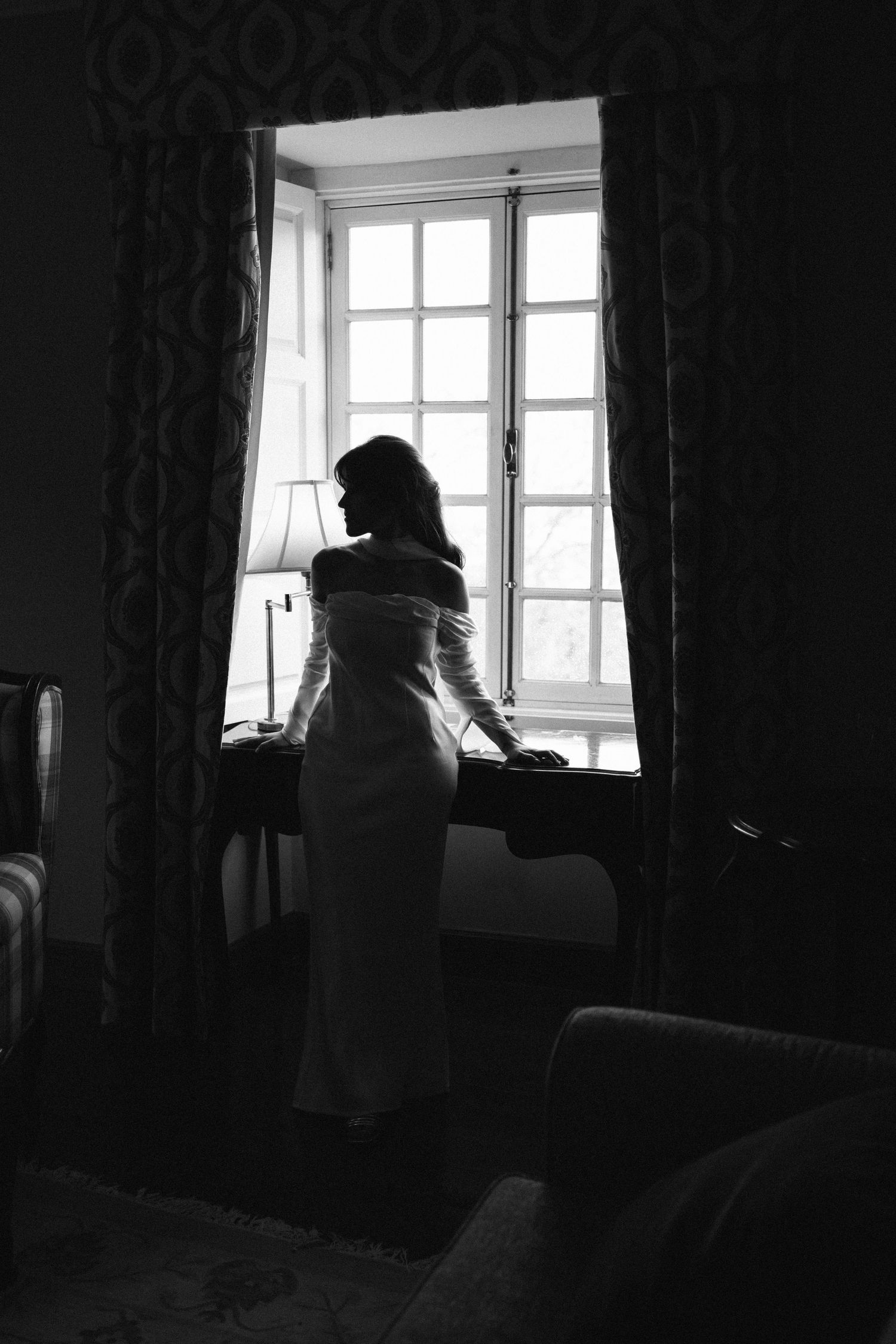 A bride silhouetted by a window in a vintage hotel room during her elopement at Lawrence's Hotel in Sintra, Portugal