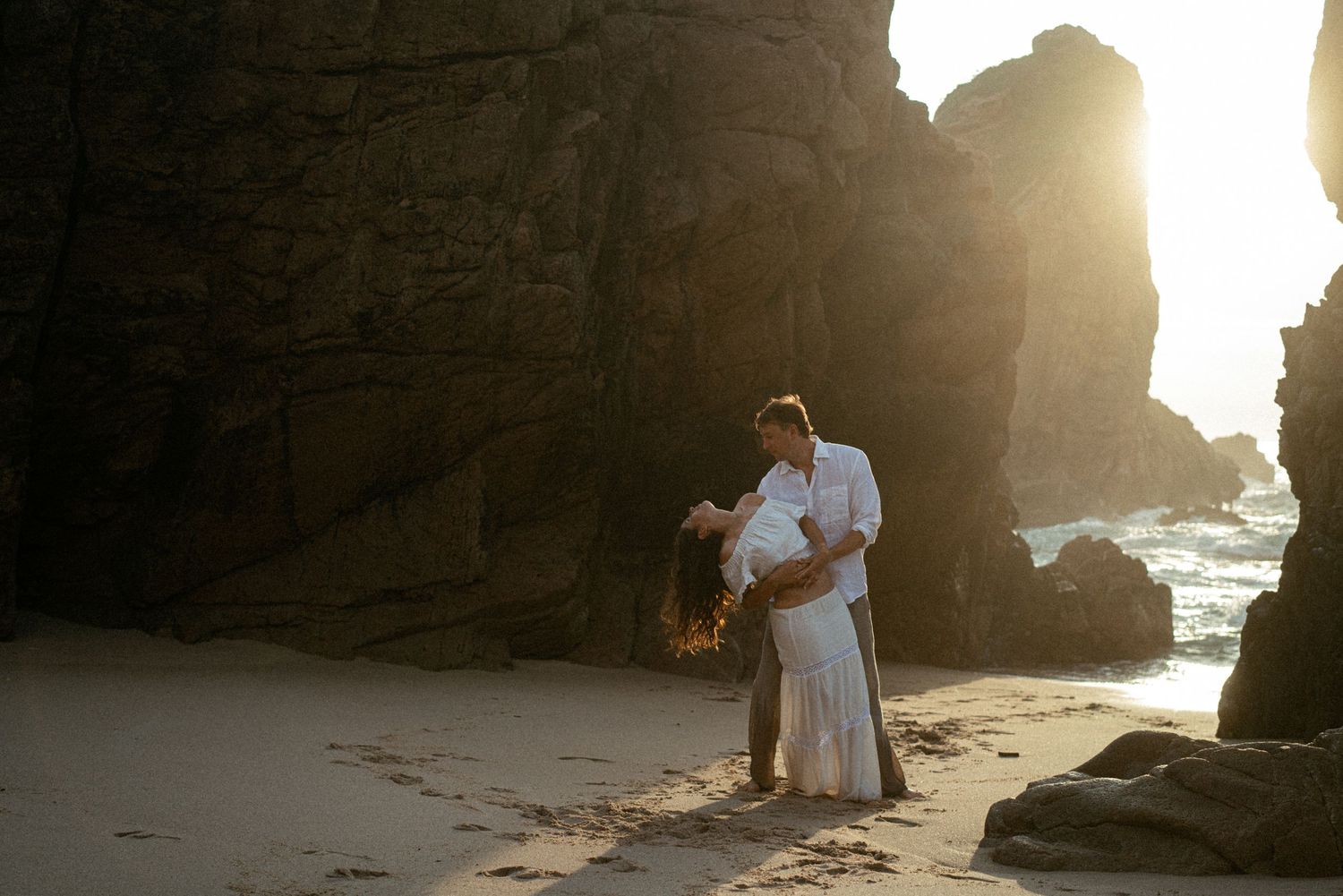 A film photograph of a couple embracing on Praia da Ursa at golden hour, elopement photography Portugal