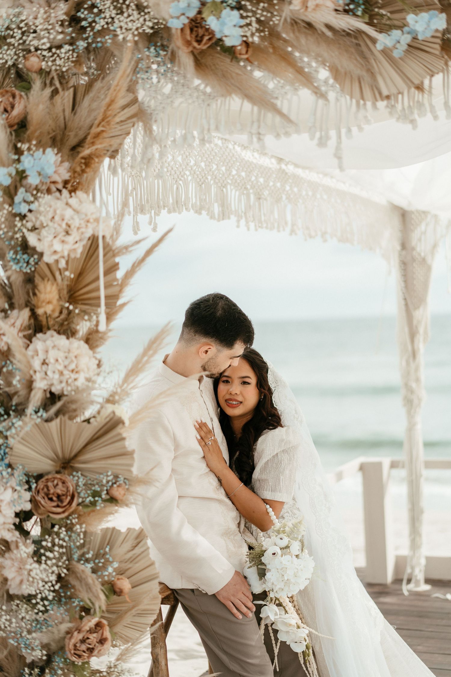 Couple under decorated floral arch at ocean beach wedding ceremony, destination wedding photography in Portugal