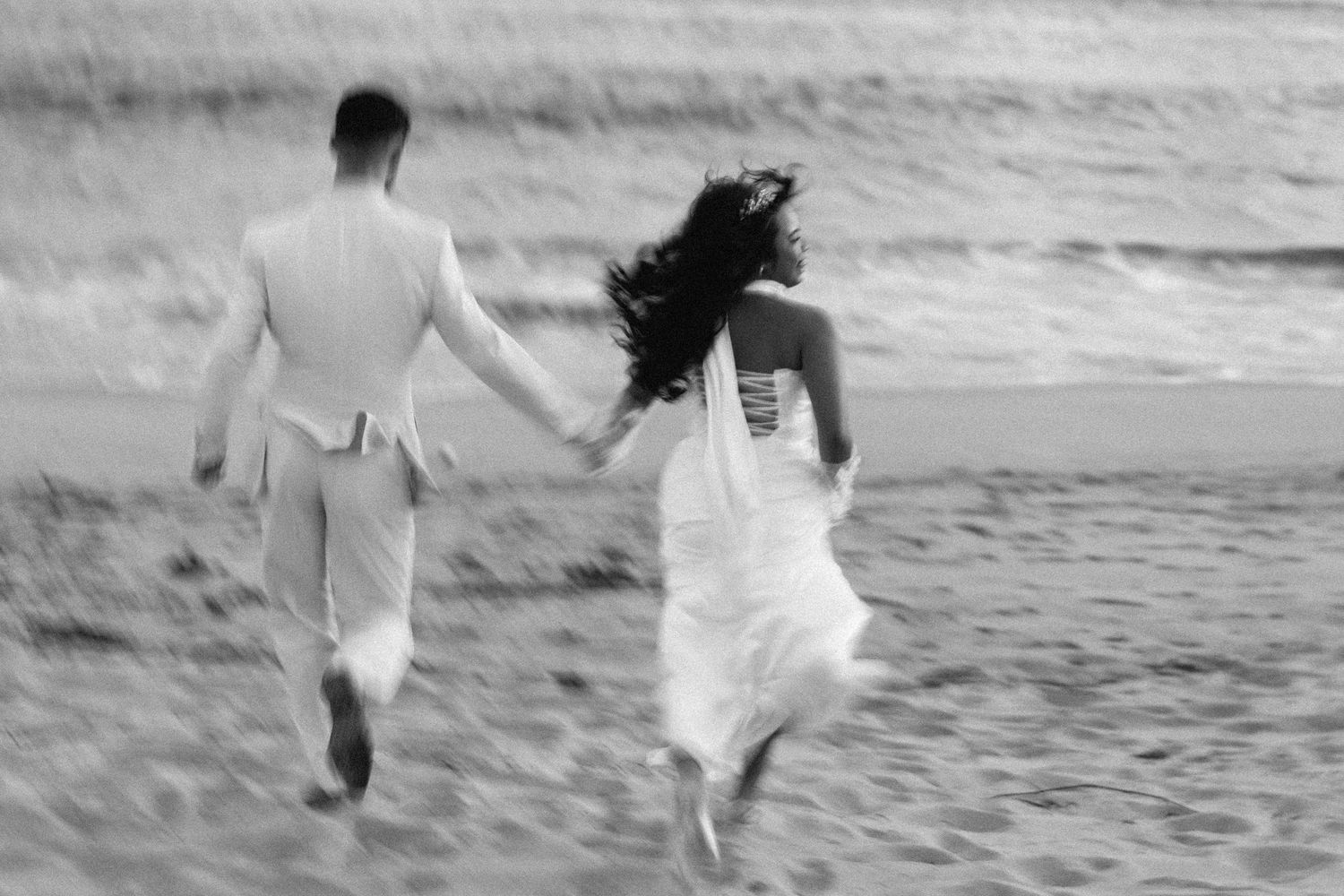 A bride and groom running together on the beach at Praia da Azurara during their wedding portraits session near Porto, Portugal