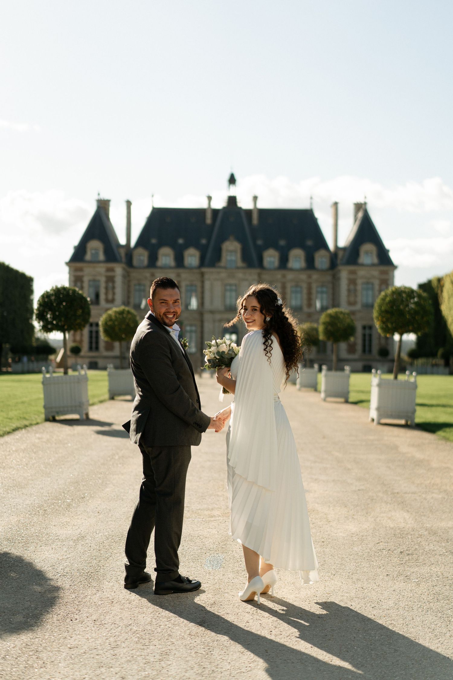 A couple standing together in front of a grand château during their wedding portrait session in France