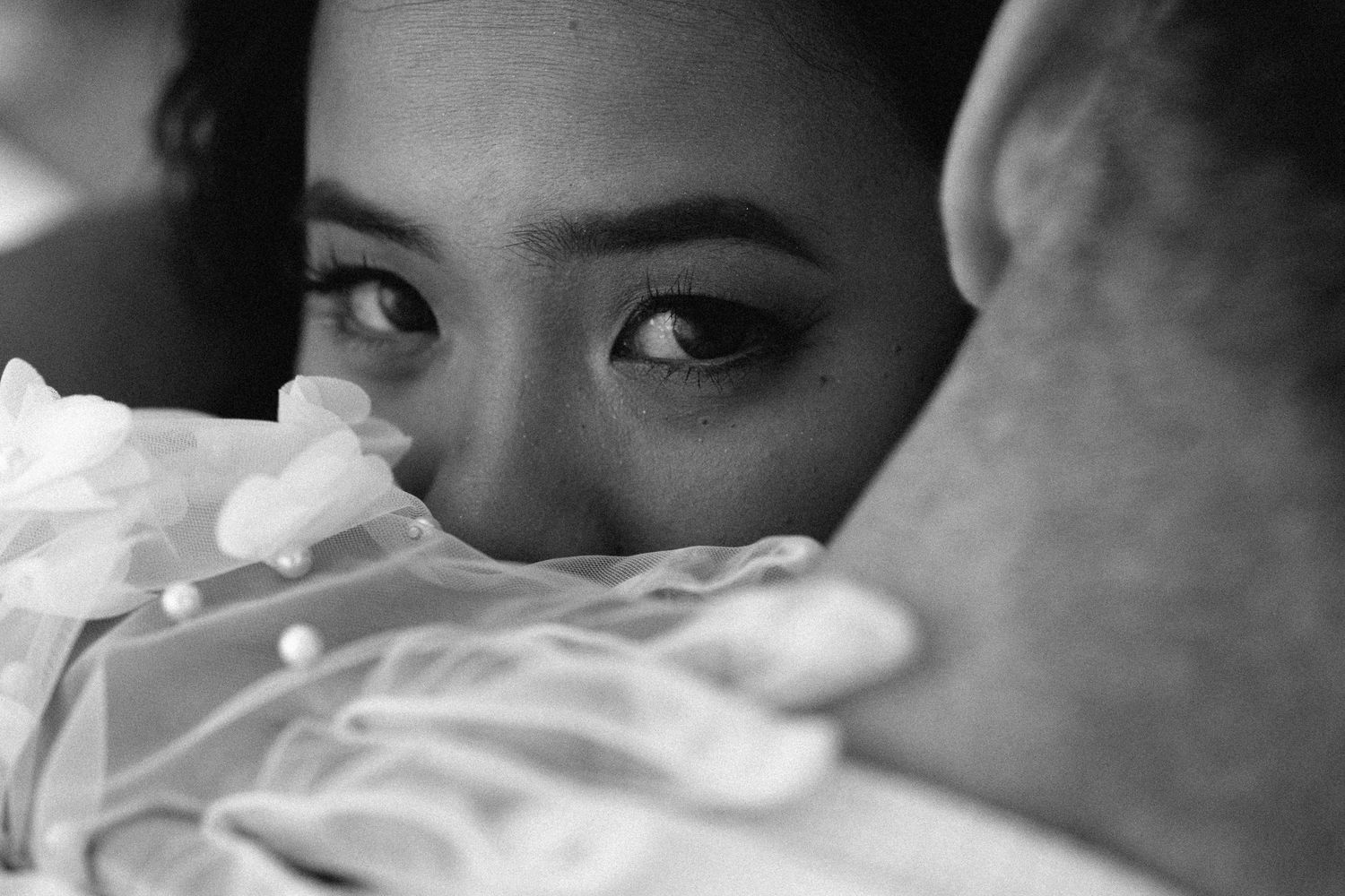A black and white close-up of a bride's face resting on her groom's chest during their wedding in Portugal