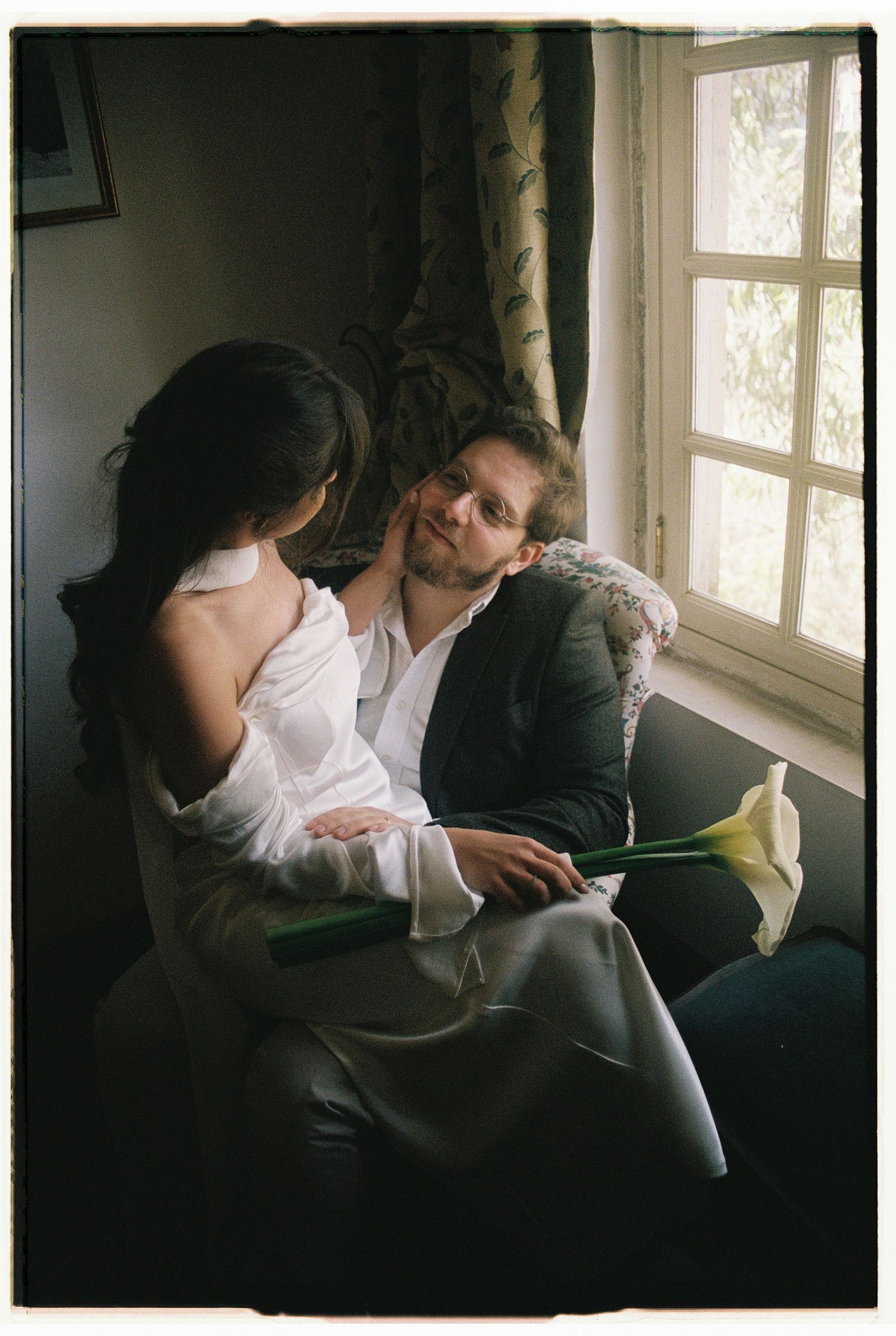 A couple sharing a quiet moment together by a sunlit window during their elopement in Sintra