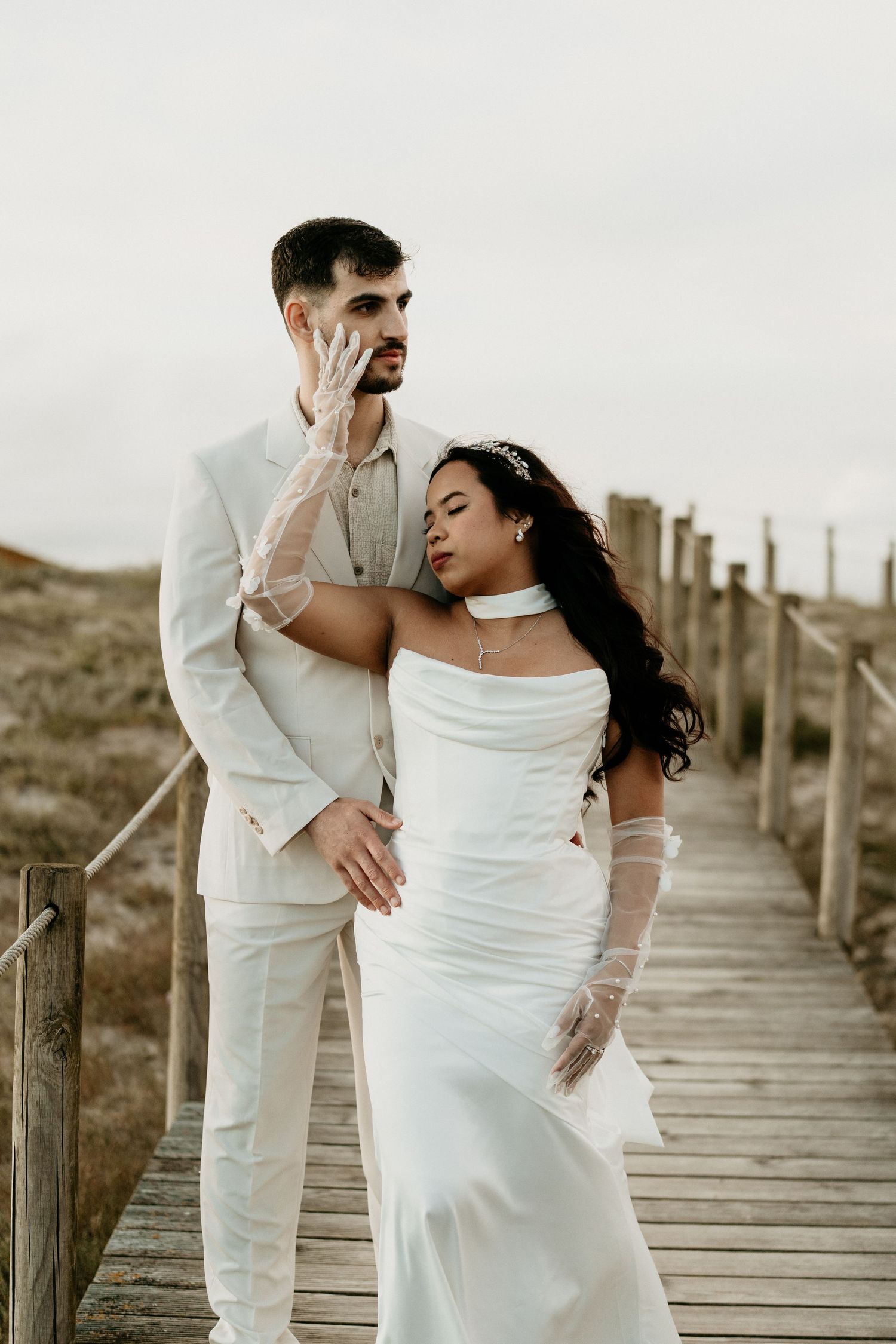 A bride and groom embracing on the coastal boardwalk during their wedding portraits session near Porto, Portugal